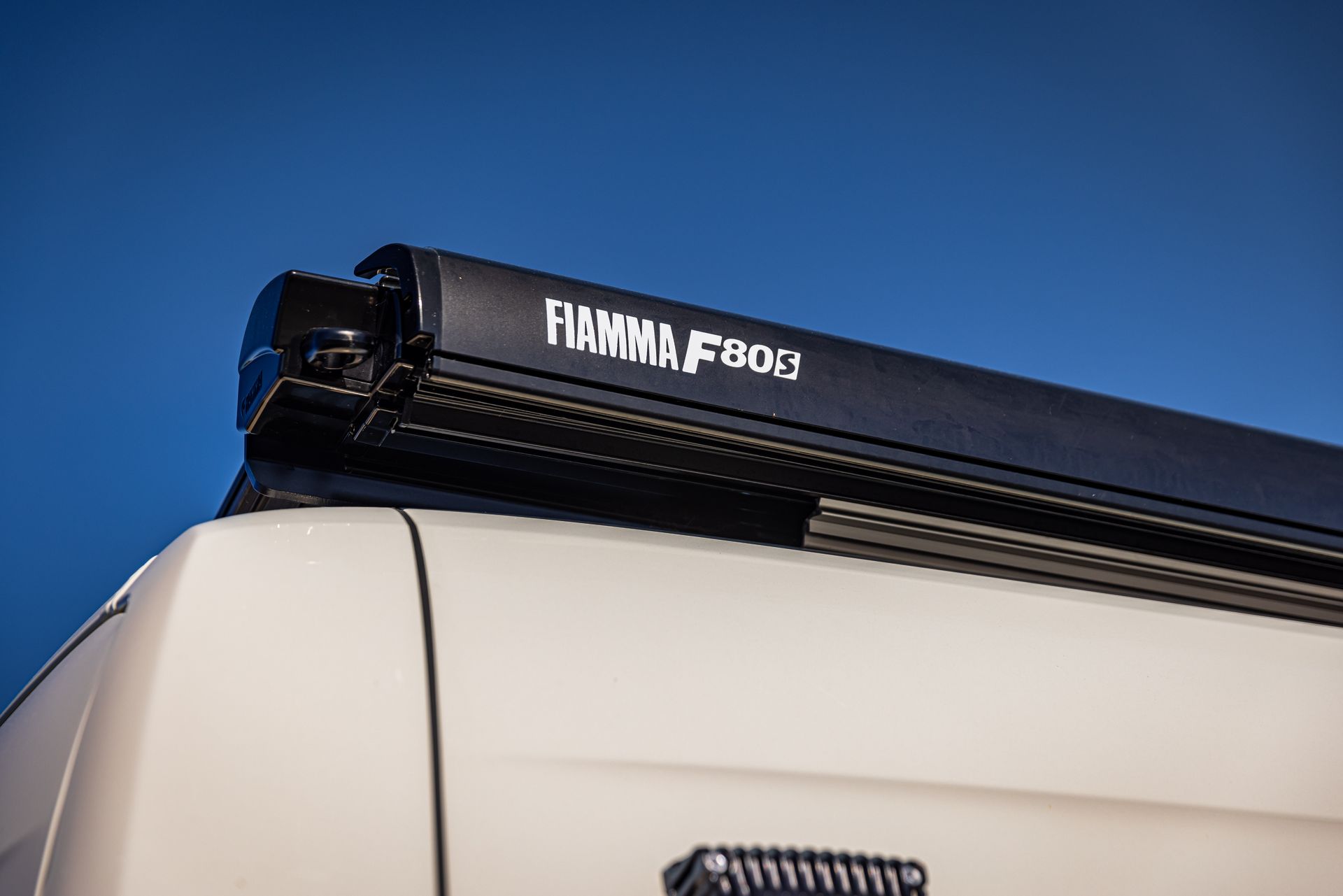 A white van with a black awning on top of it.