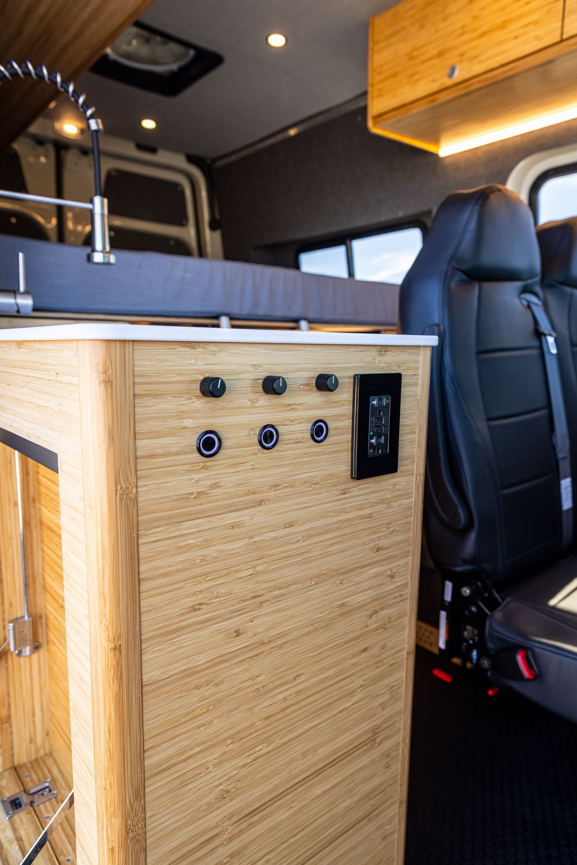 The inside of a van with a wooden cabinet and a sink.