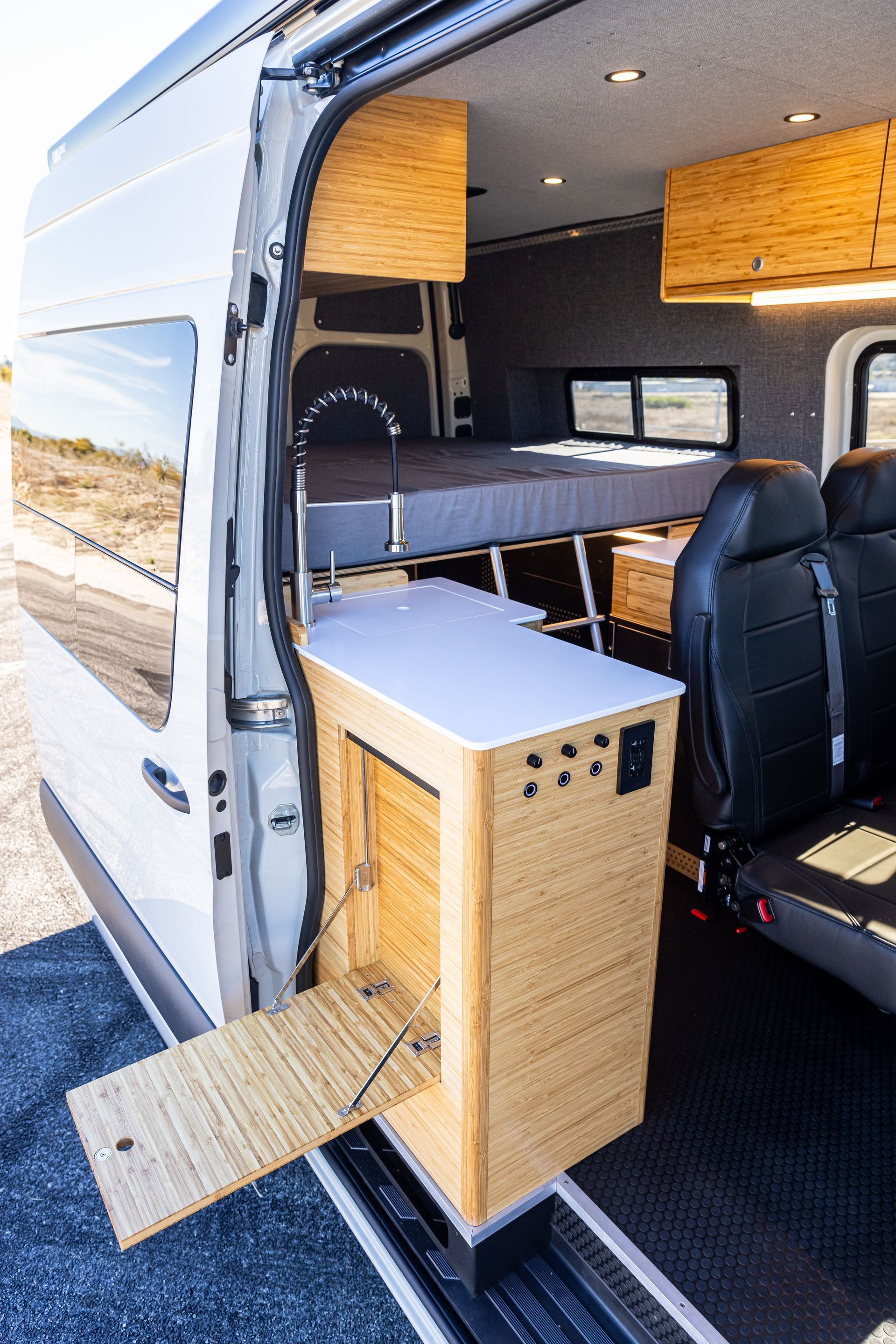 The back of a van with a bed and a table in it.