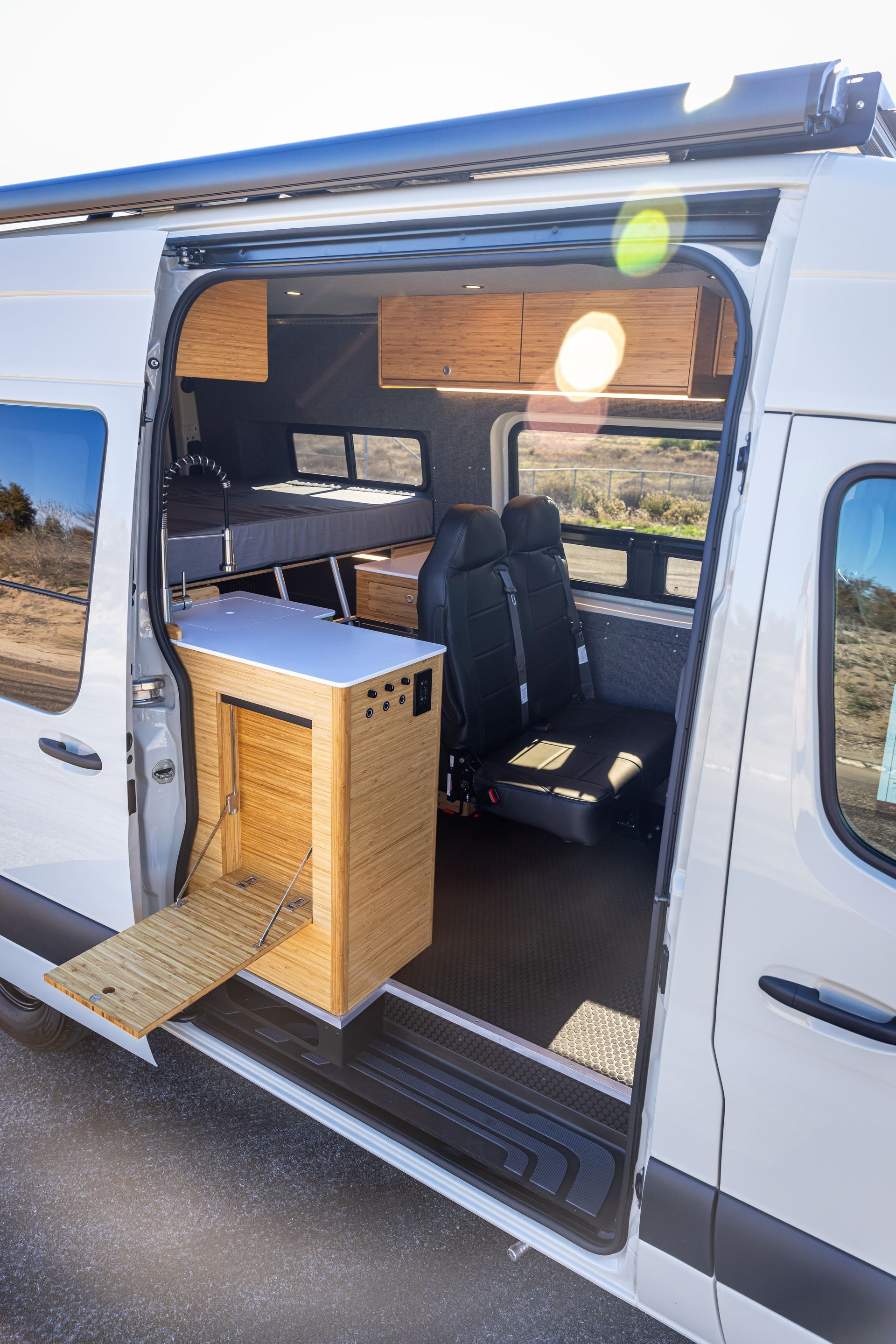 A white van with the door open and a wooden box in the back.
