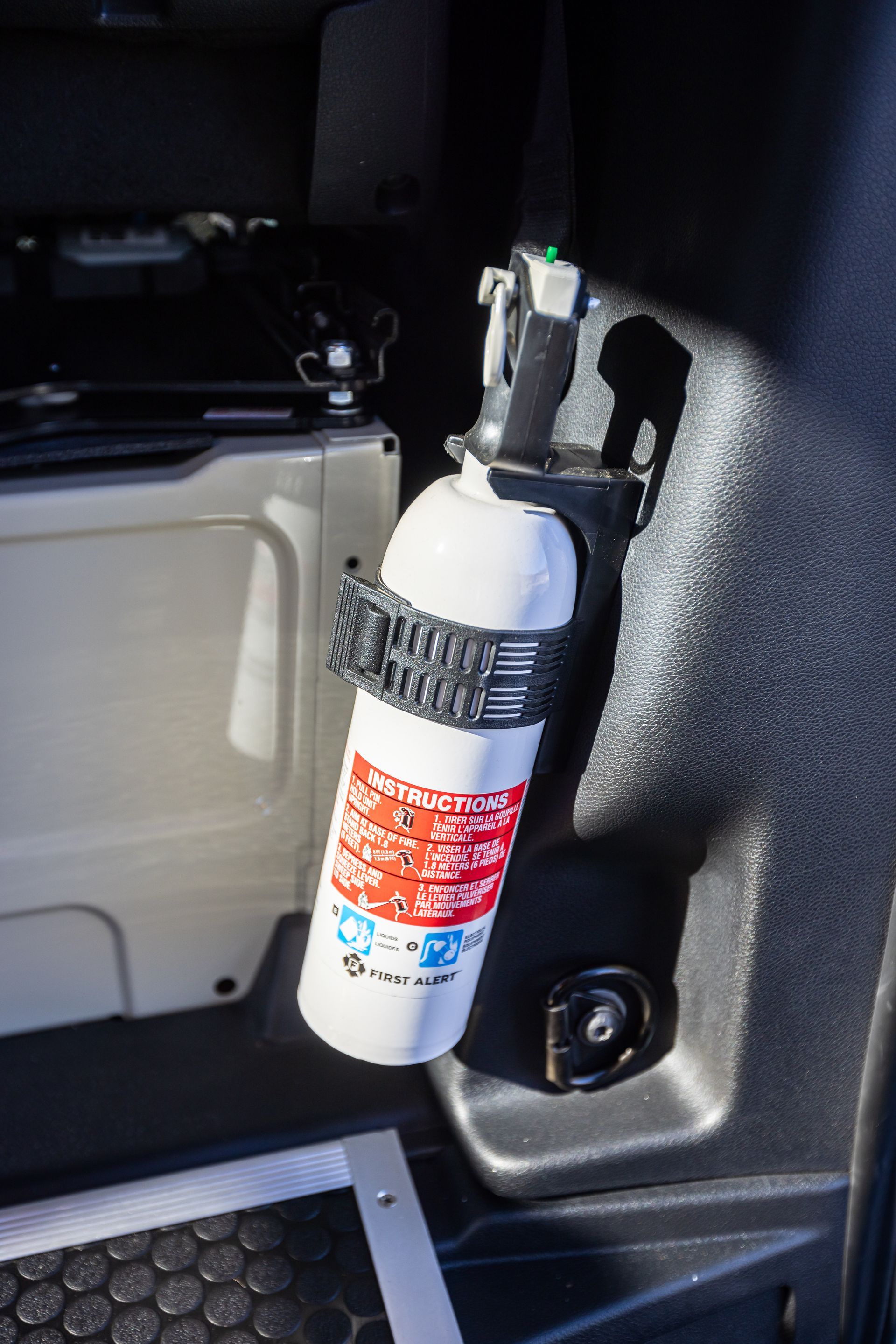 A fire extinguisher is hanging from the side of a car.