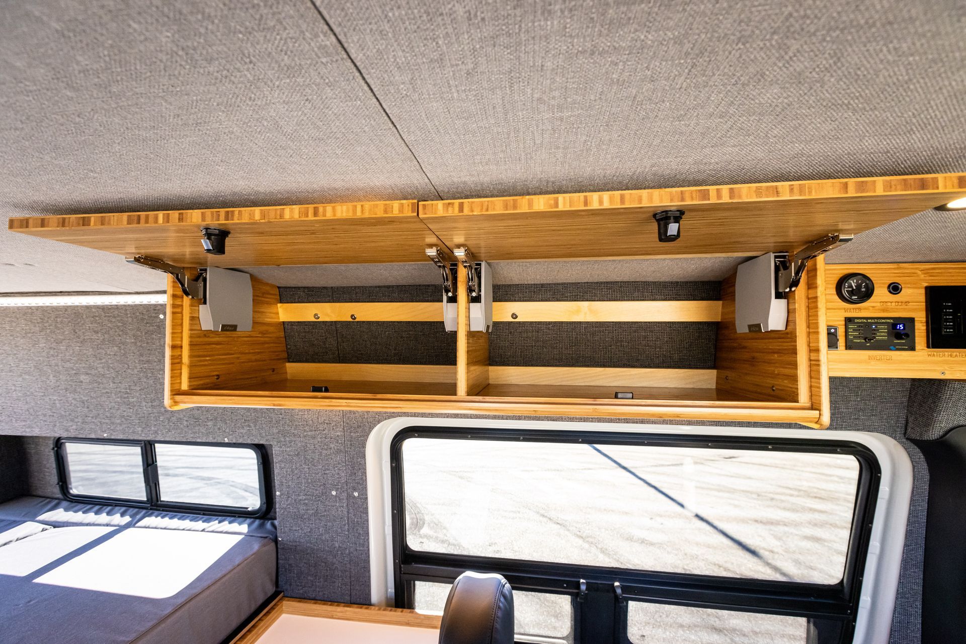The inside of a camper van with a wooden shelf hanging from the ceiling.
