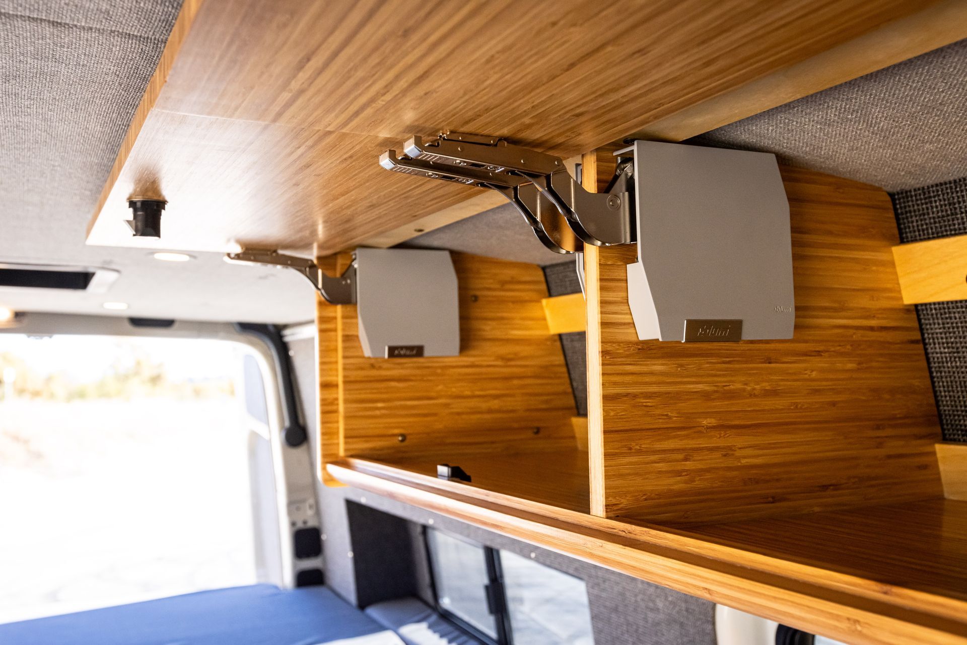 The inside of a van with wooden shelves and speakers.