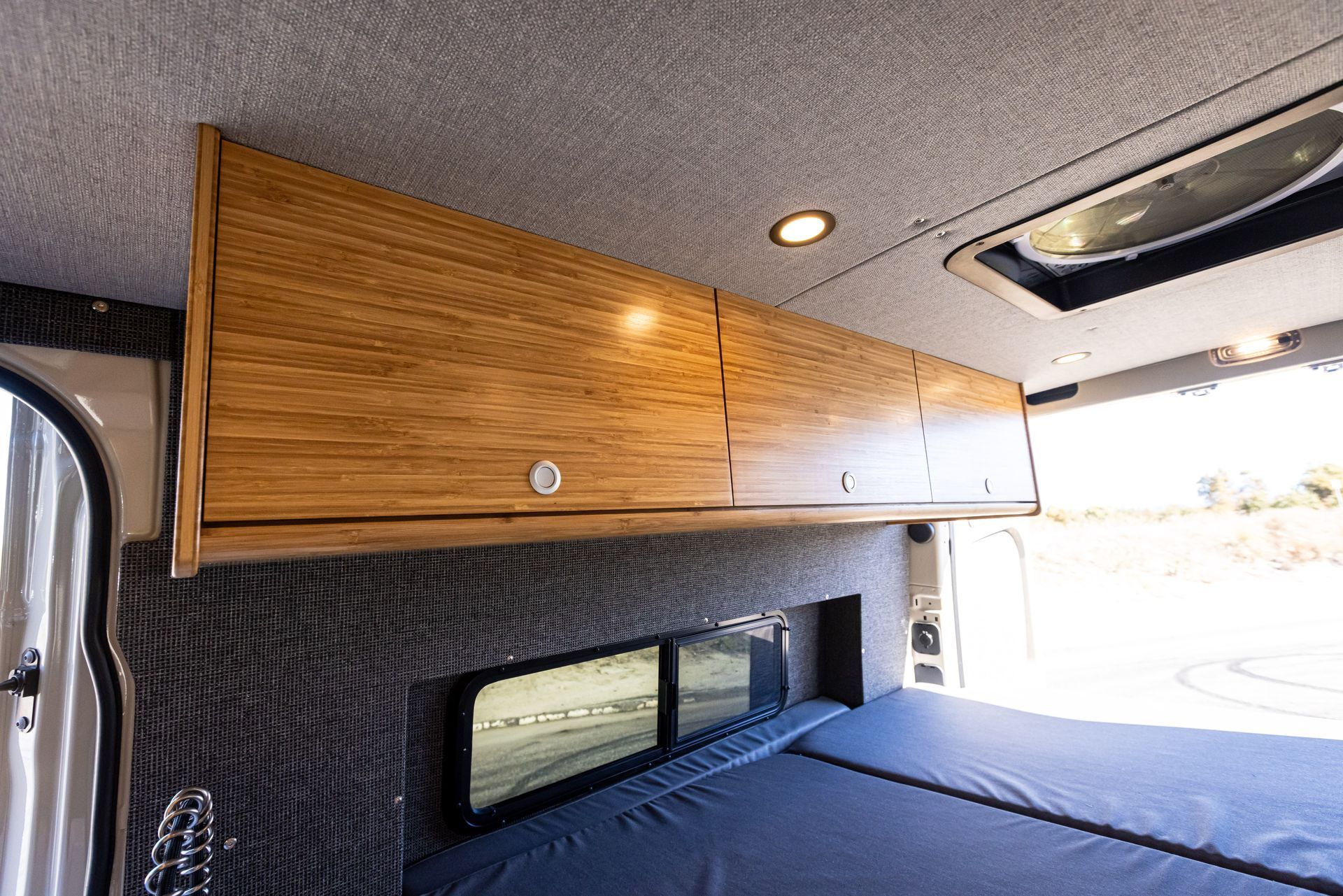 The inside of a van with a bed and cabinets.