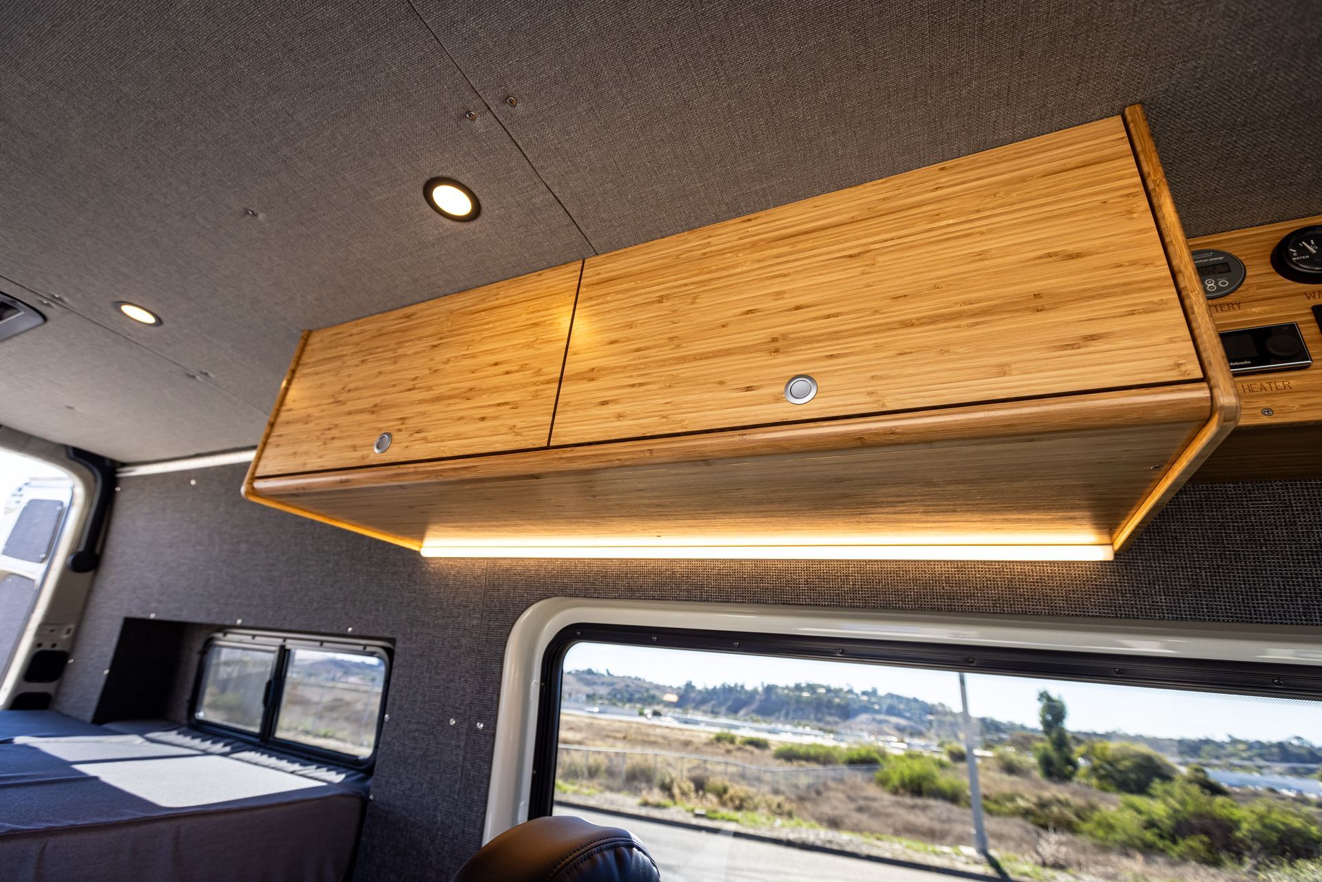 A wooden cabinet is hanging from the ceiling of a van.