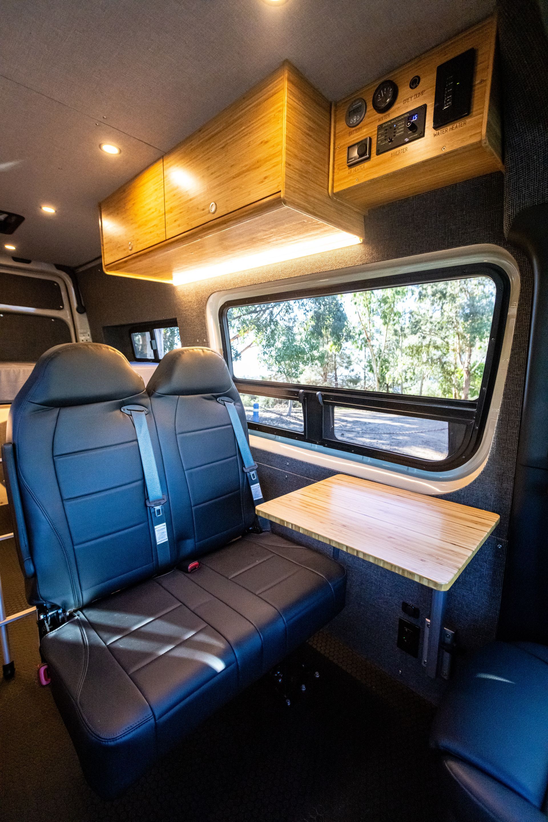 The back seat of a van with two seats and a table.