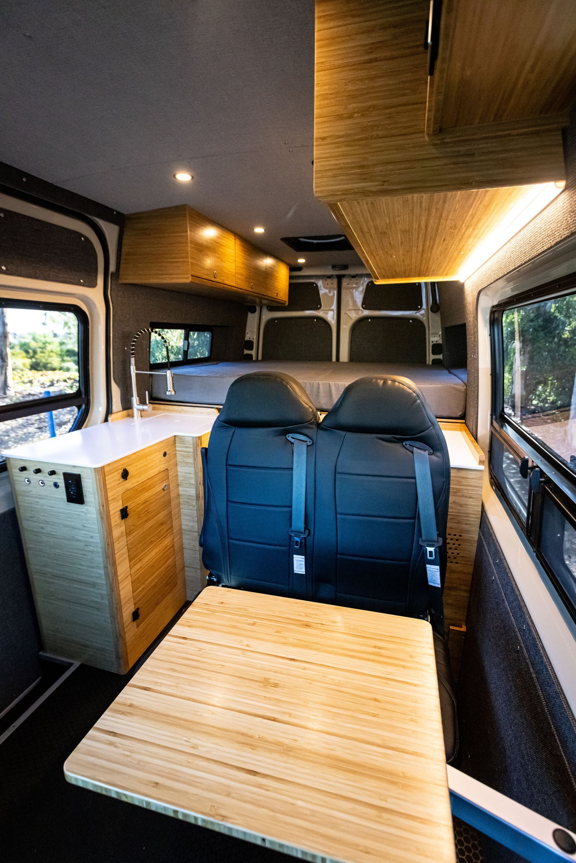 The inside of a van with a table and a bed.