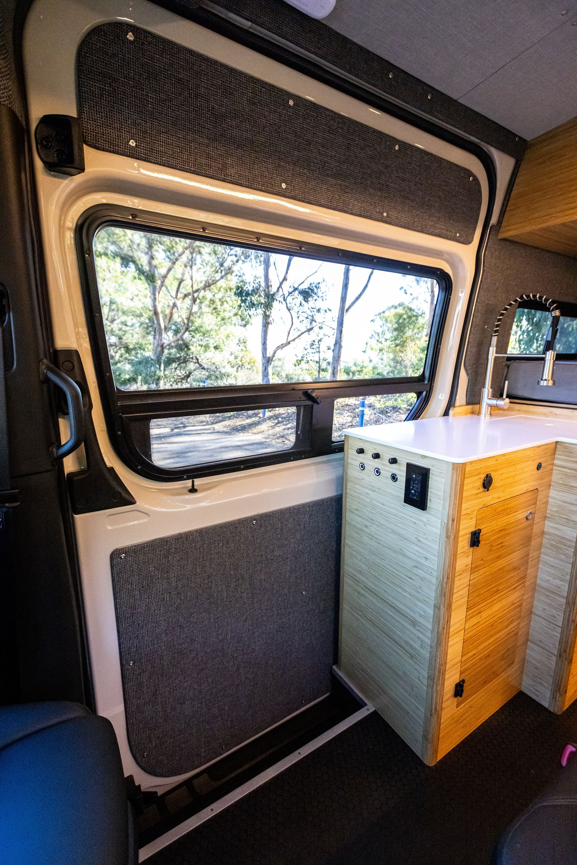 The inside of a van with a window and a sink.