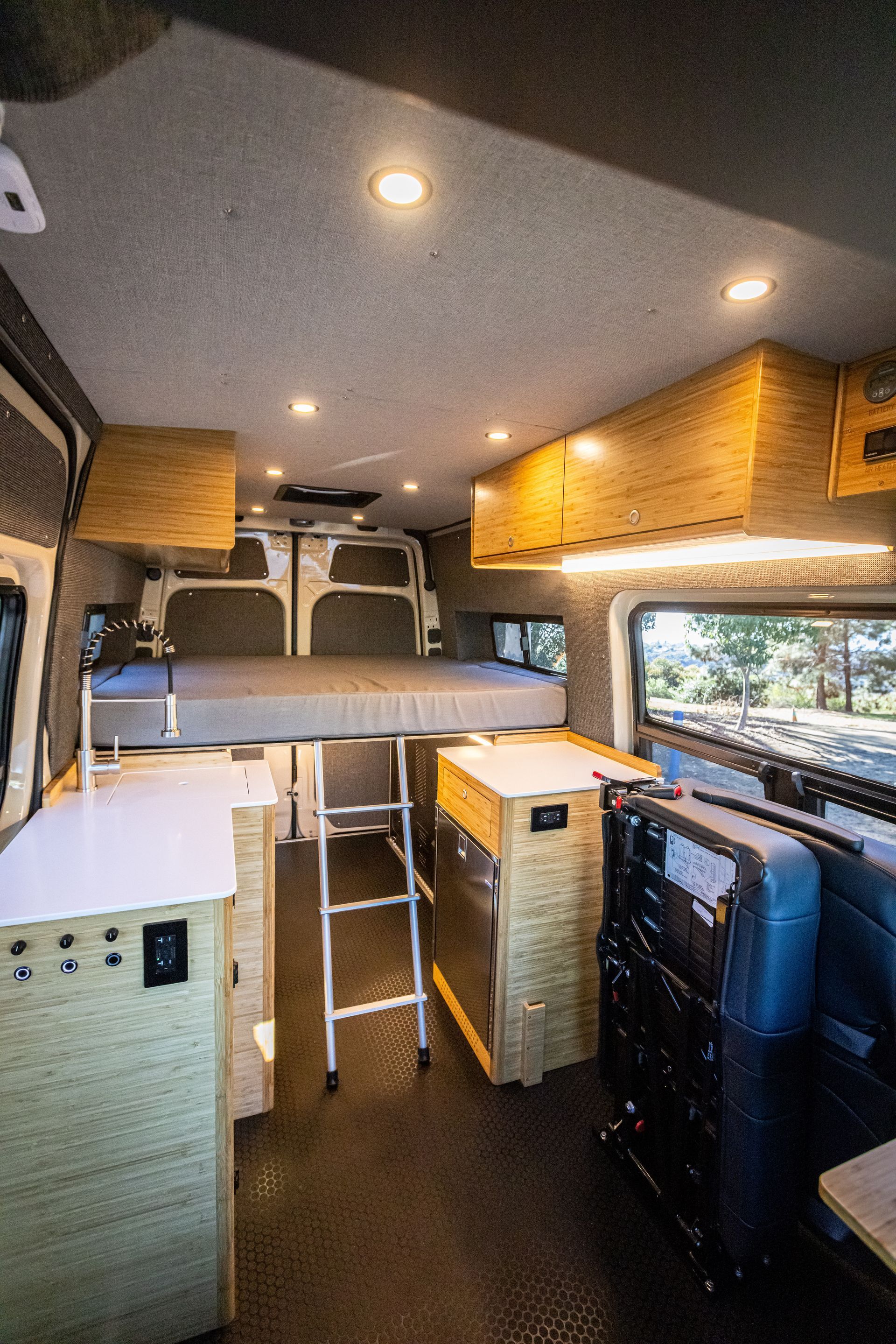 The inside of a camper van with a bed and a kitchen.