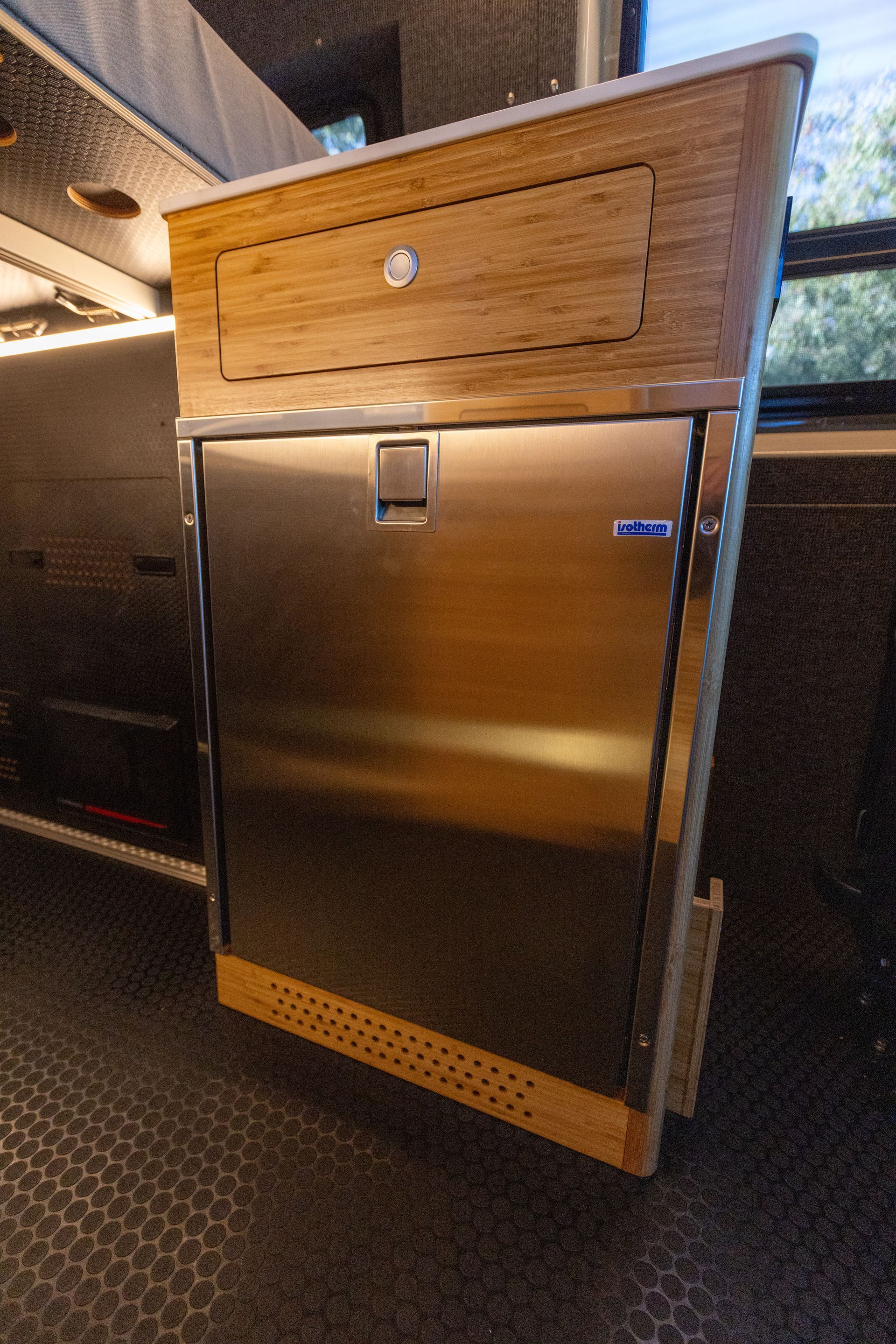 a stainless steel refrigerator is sitting under a wooden cabinet .