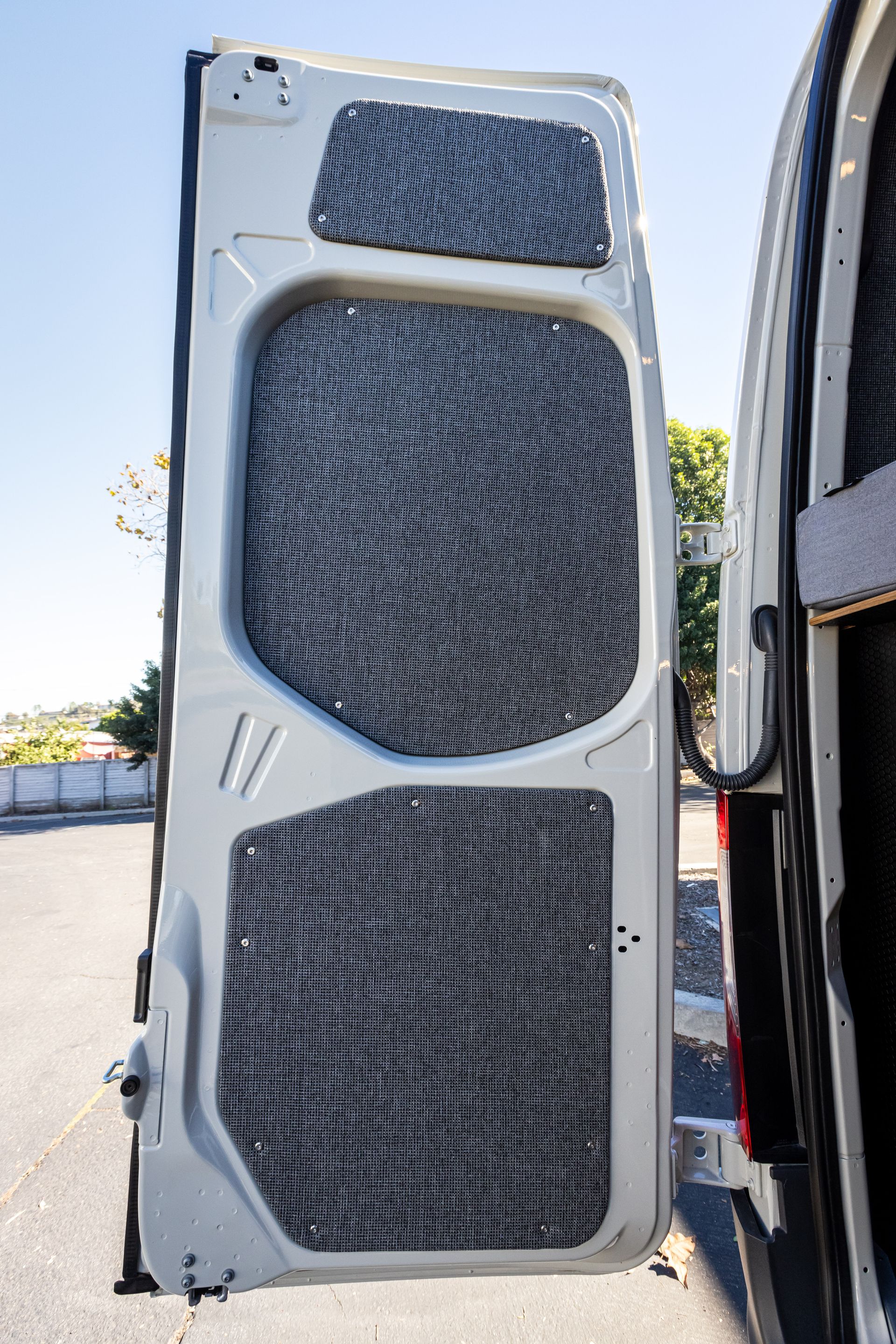 the back door of a white van is open and has a carpet on it .