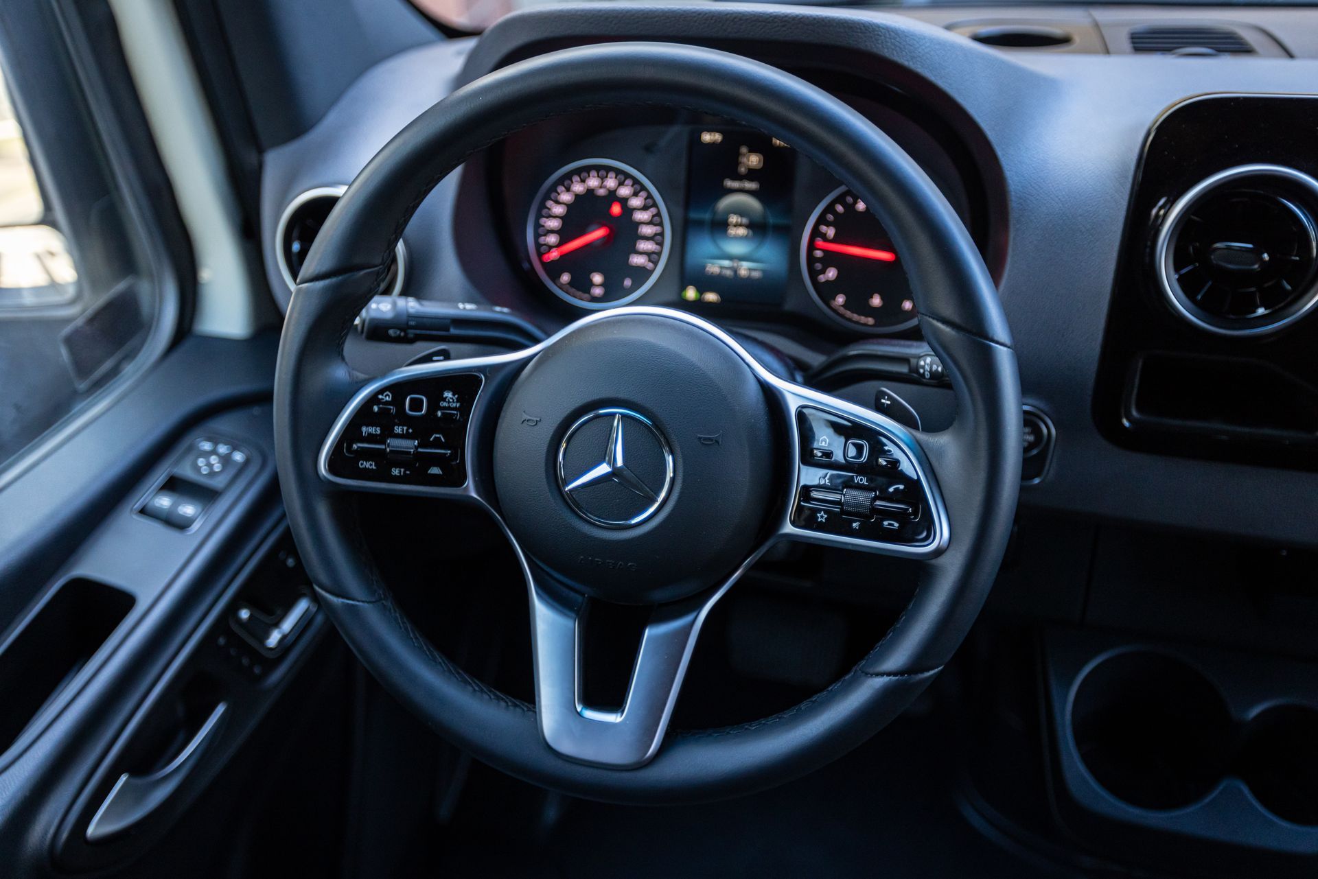A close up of a mercedes steering wheel and dashboard