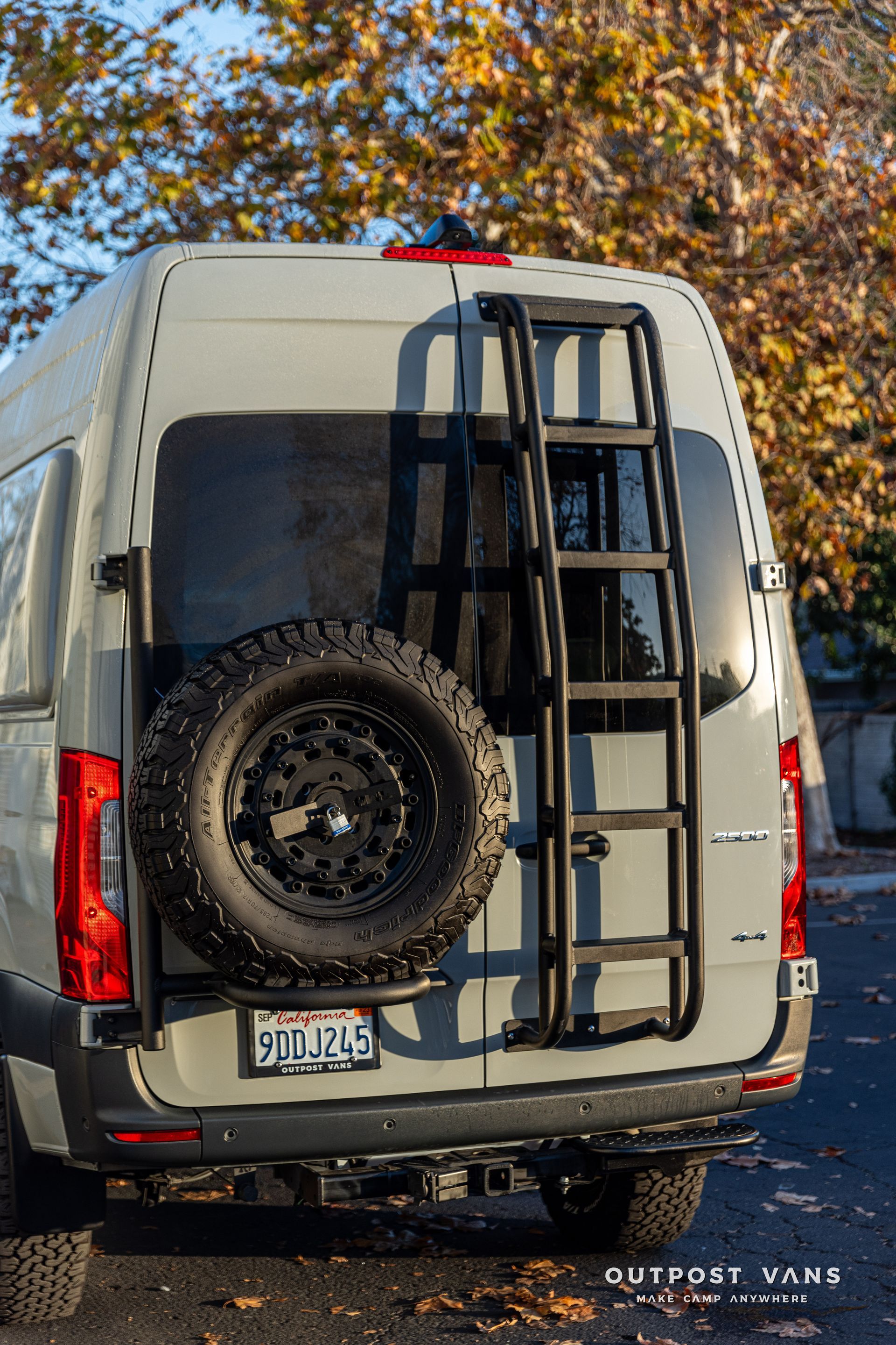 a van with a ladder attached to the back of it is parked on the side of the road .