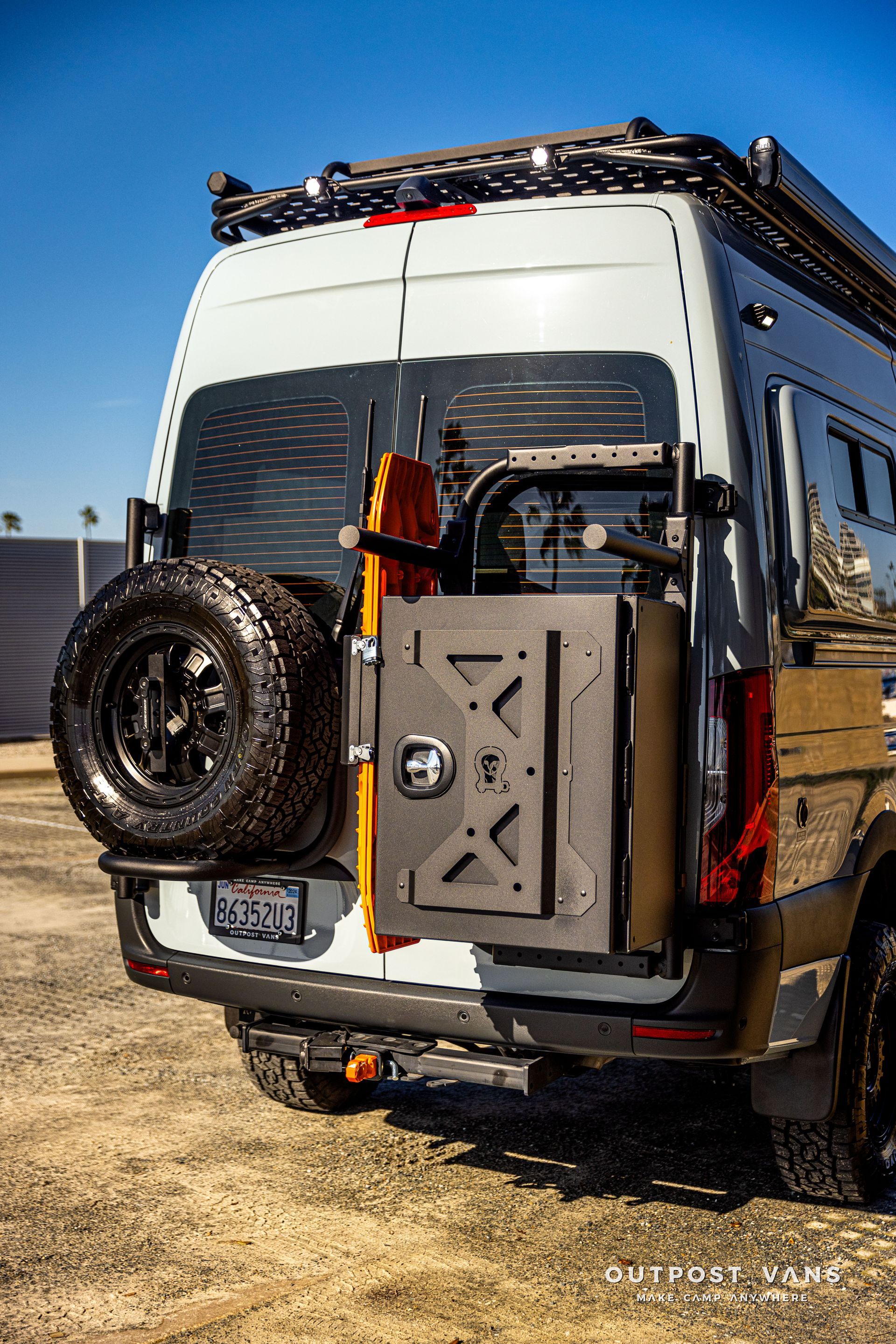 the back of a van with a tire rack and a toolbox attached to it .
