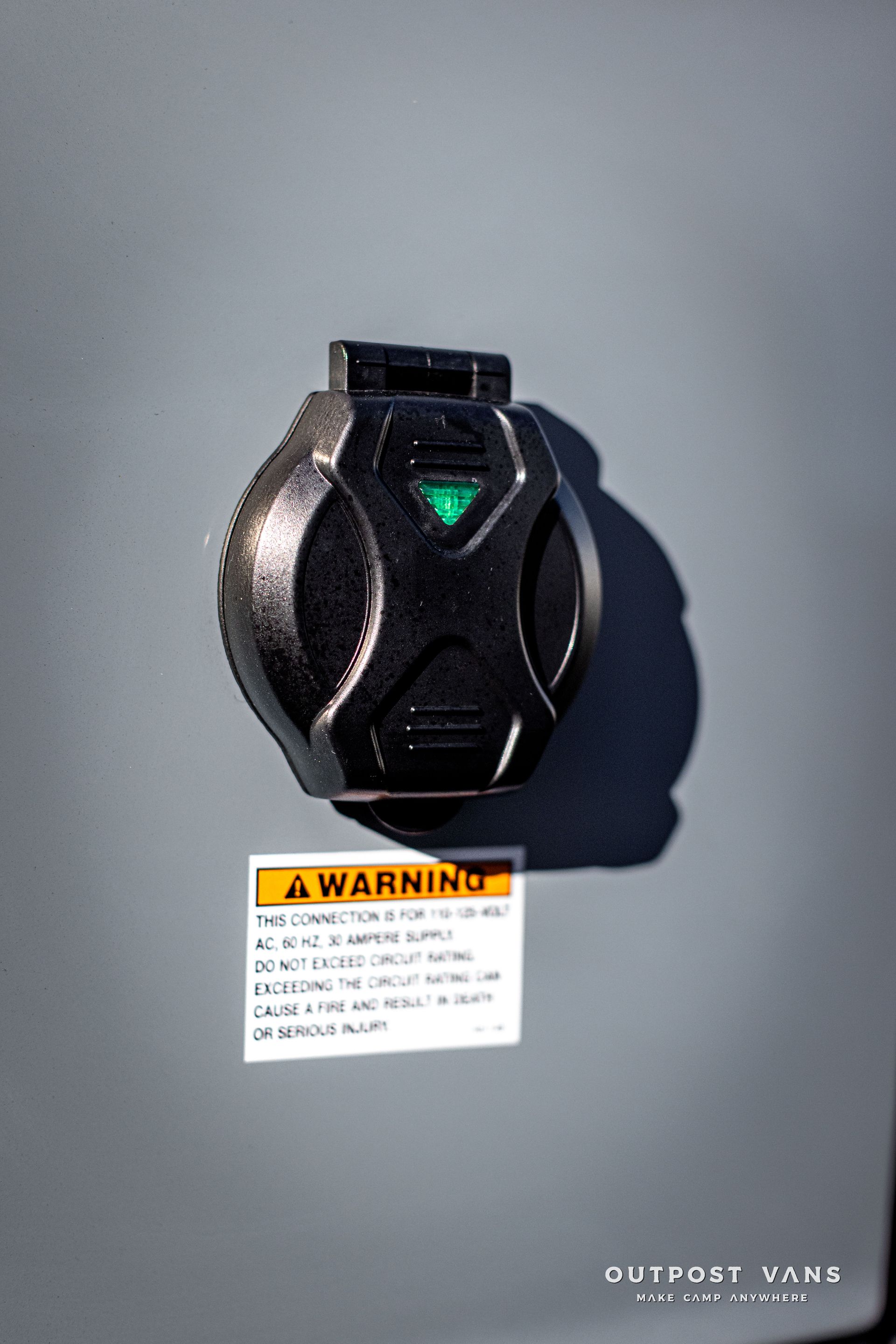 a black electrical outlet with a warning sign on it .