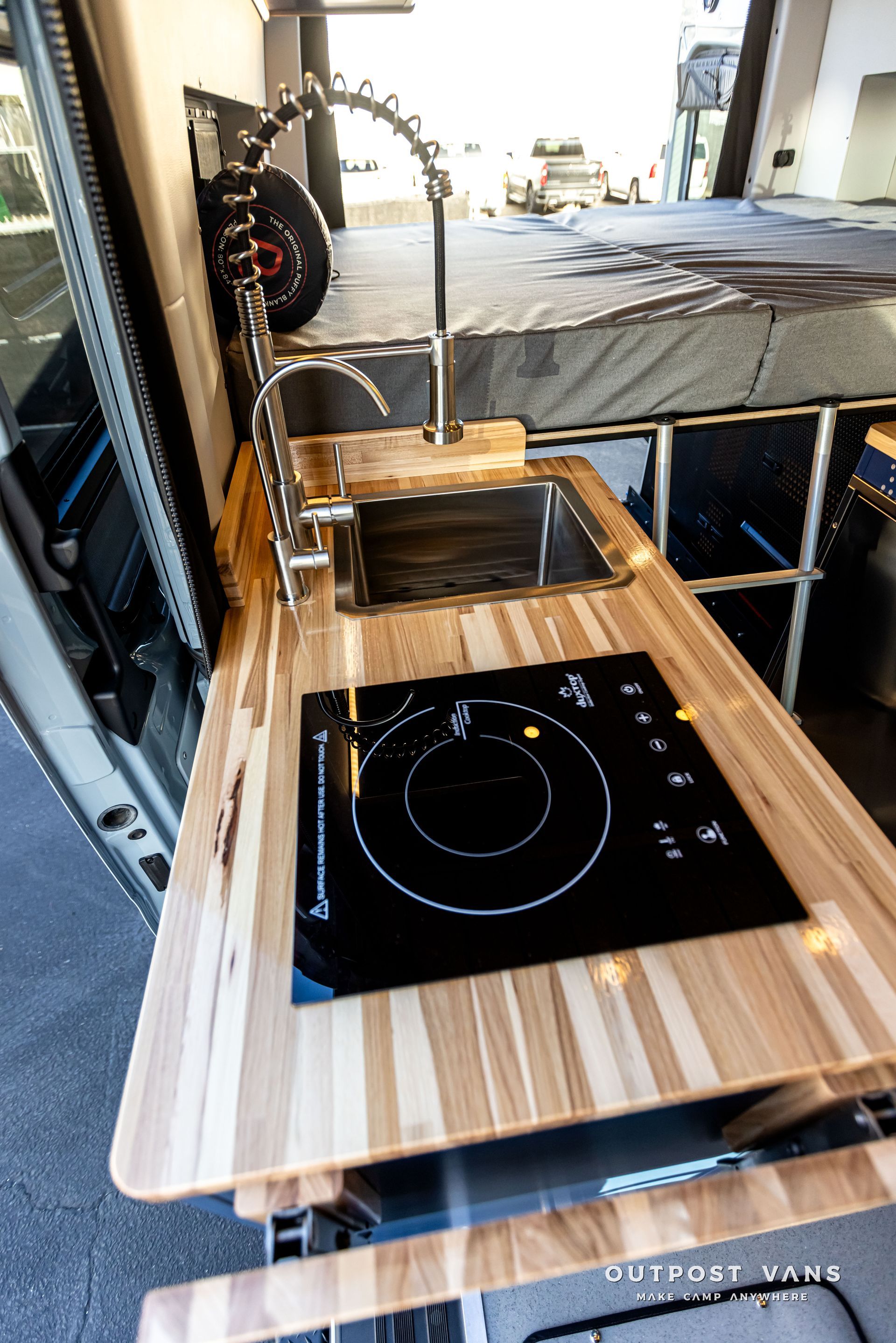 A kitchen in a van with a sink and stove top oven.