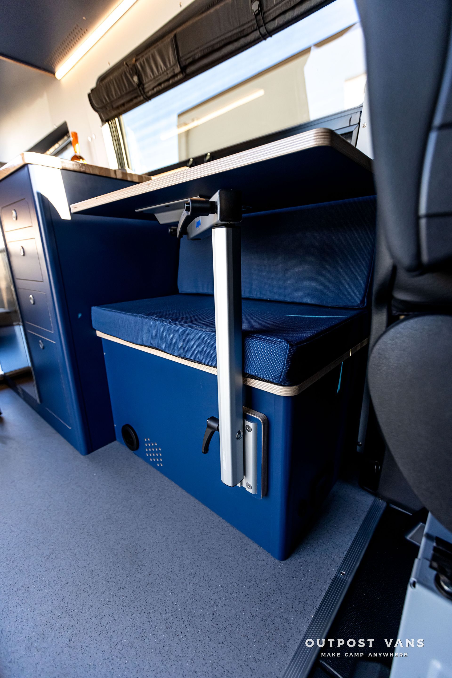A blue bench with a table attached to it in a van.
