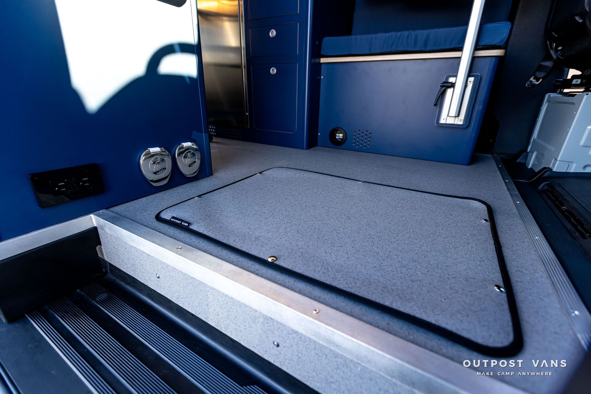 A blue van with a gray mat on the floor