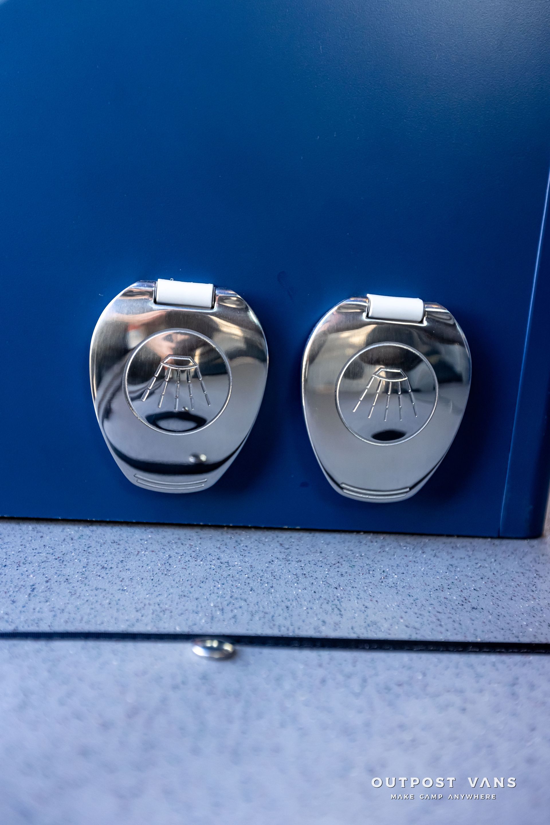 A pair of silver toilet seats on a blue wall