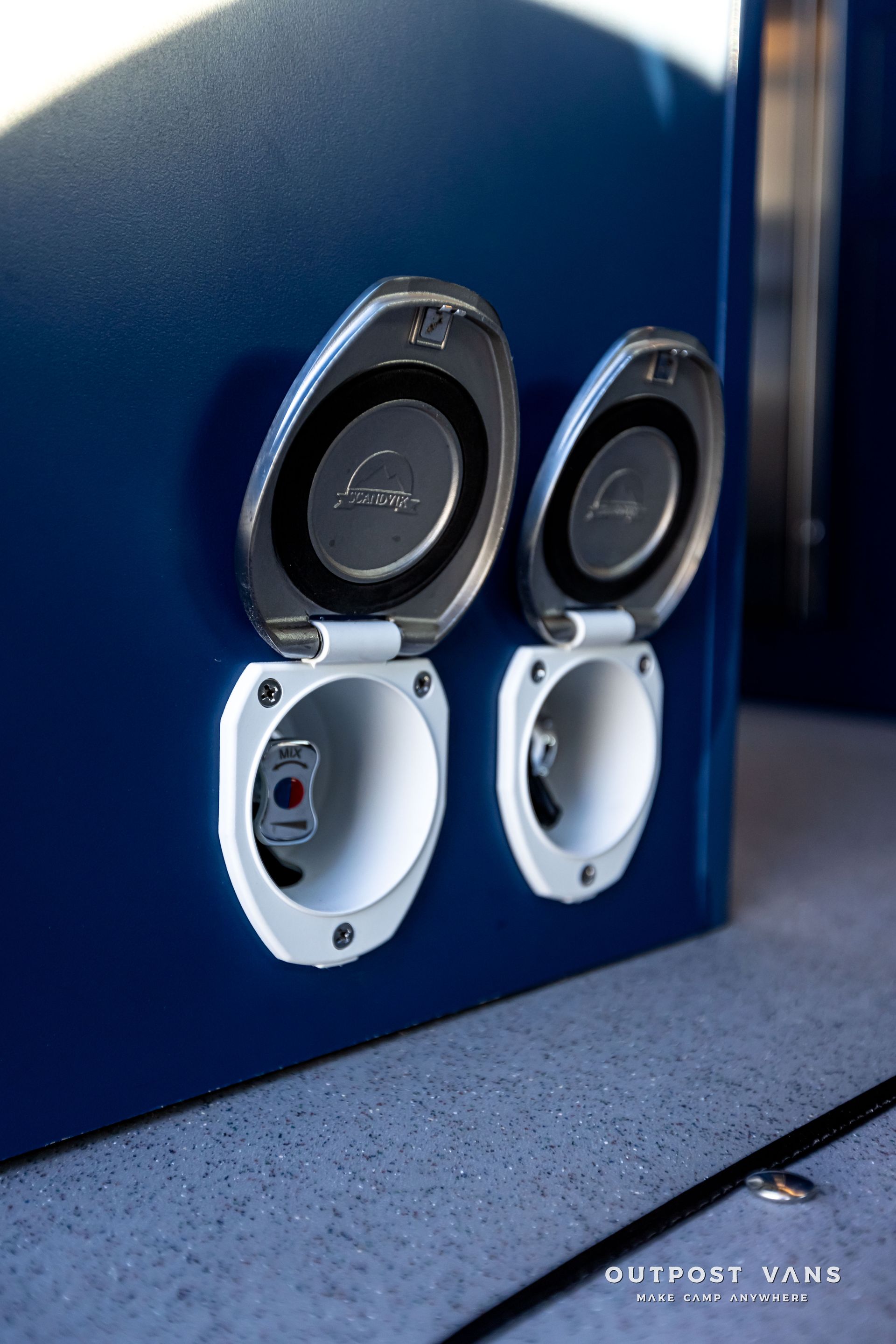 A close up of two electrical outlets on a blue wall.
