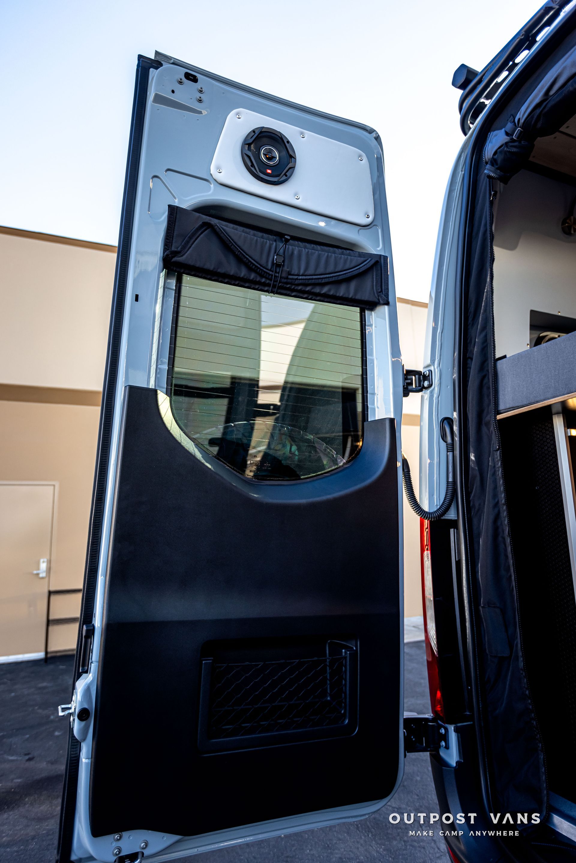 A van with the door open and a speaker on top of it.