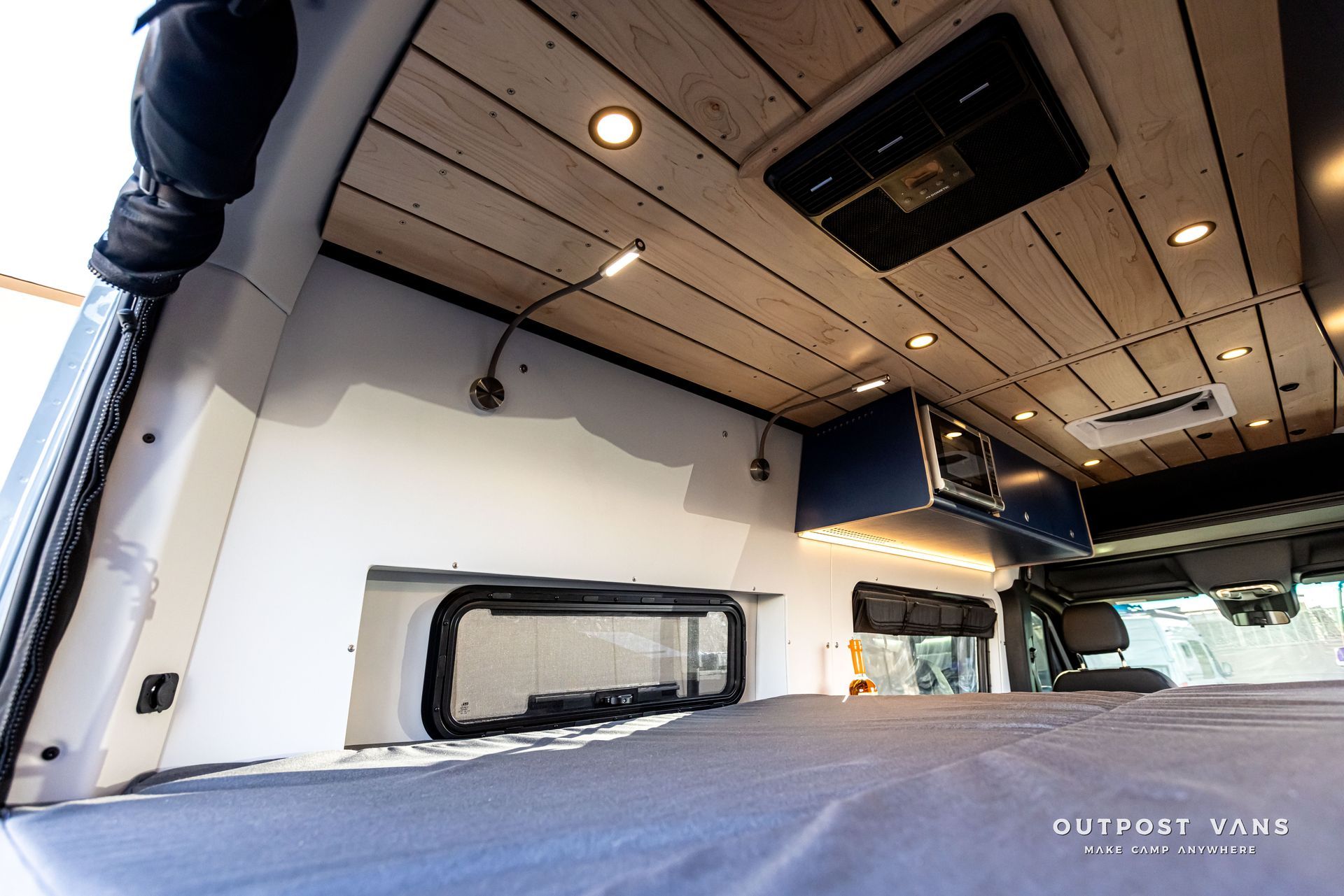 The inside of a van with a bed and a ceiling fan.