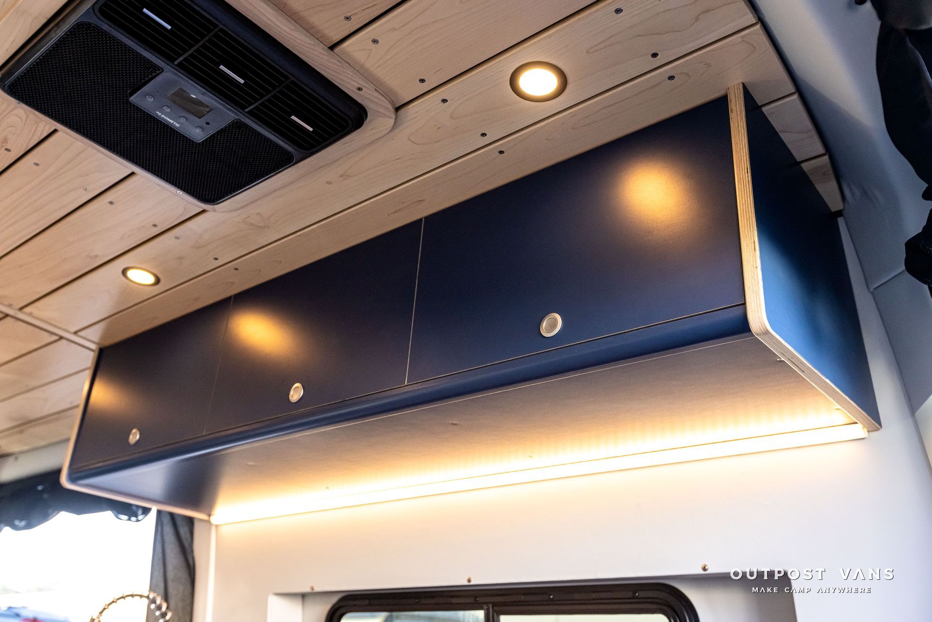A blue cabinet is hanging from the ceiling of a van.