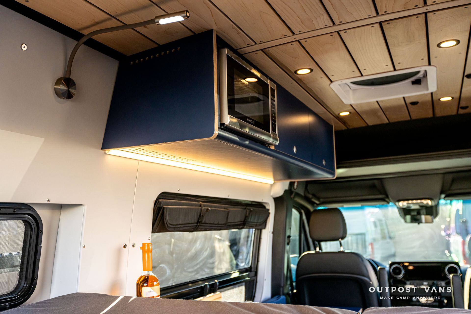 The inside of a van with a bed and a microwave.