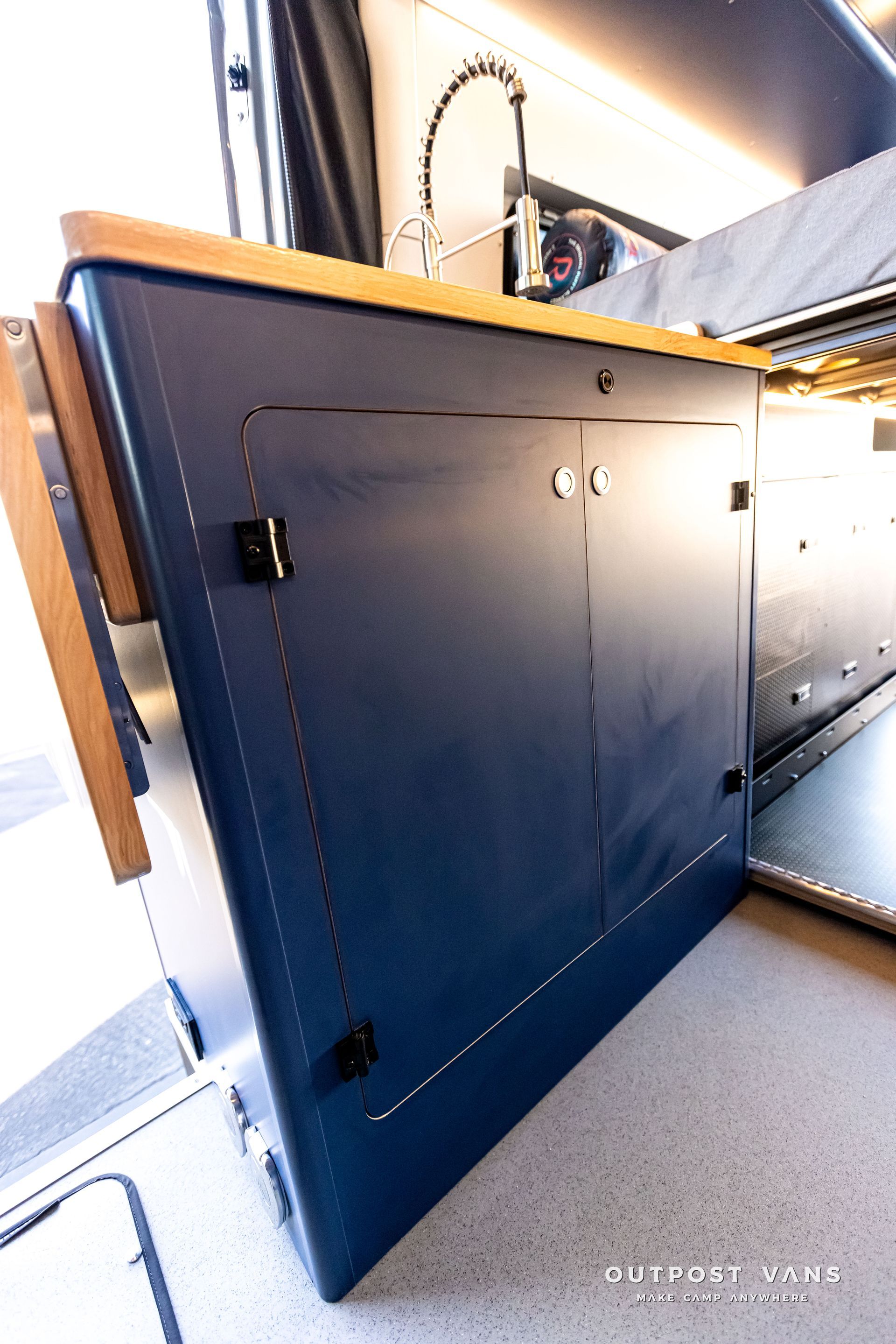 A blue cabinet with a wooden counter top in a kitchen.