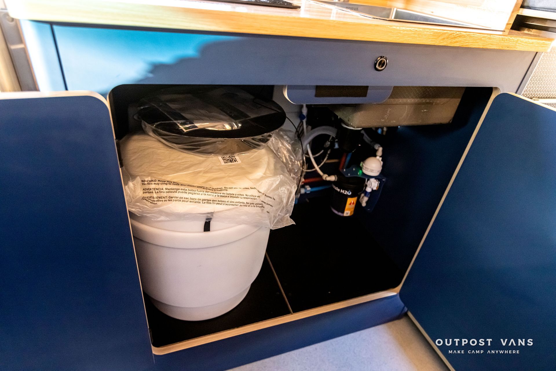 A white toilet is sitting under a blue cabinet.