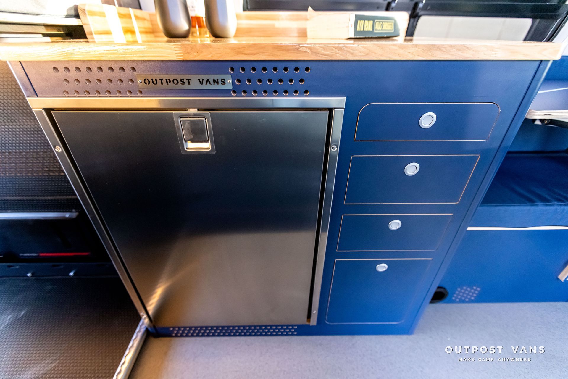 A stainless steel refrigerator is sitting under a blue cabinet in a kitchen.