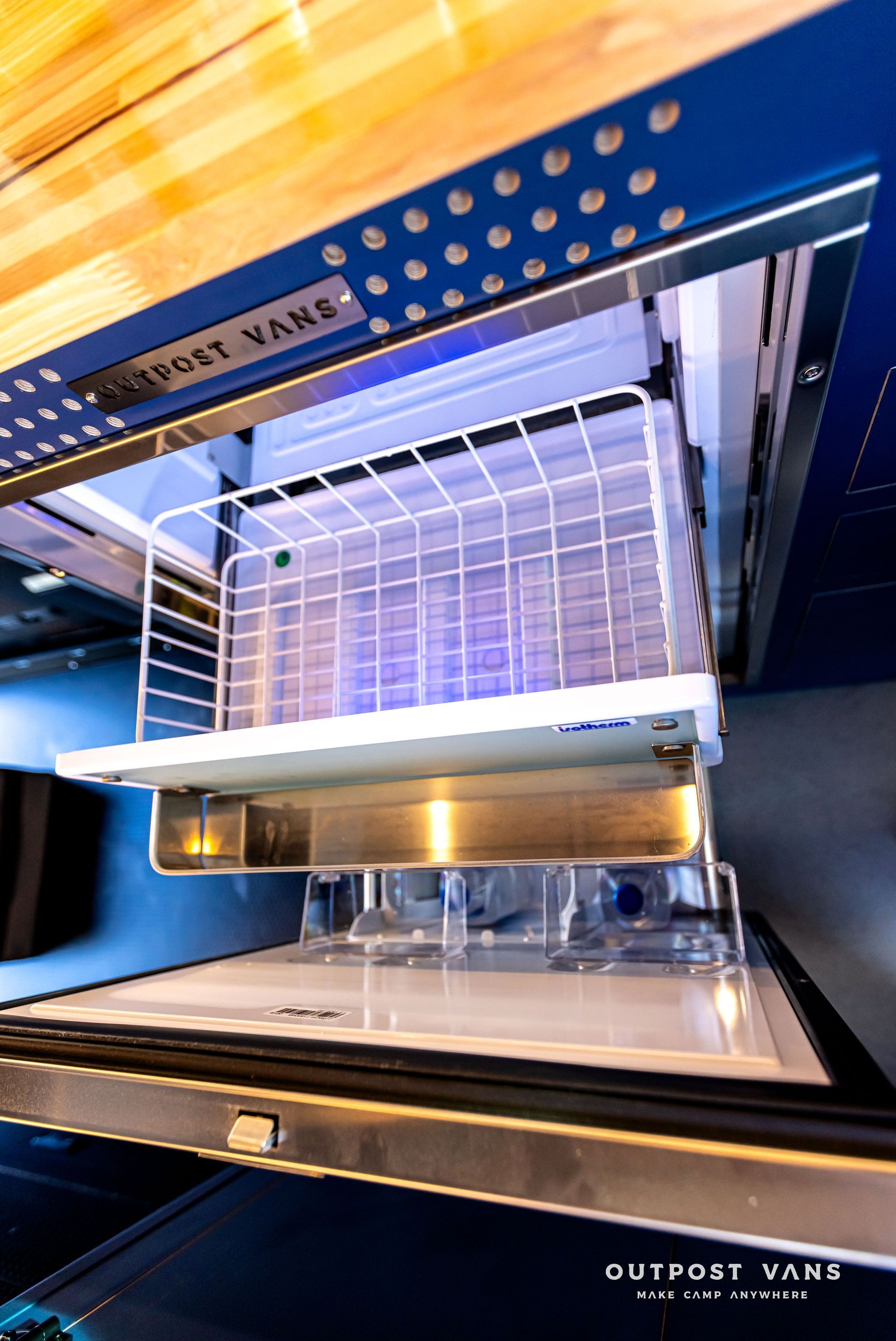 The inside of a refrigerator with a wire basket in it.