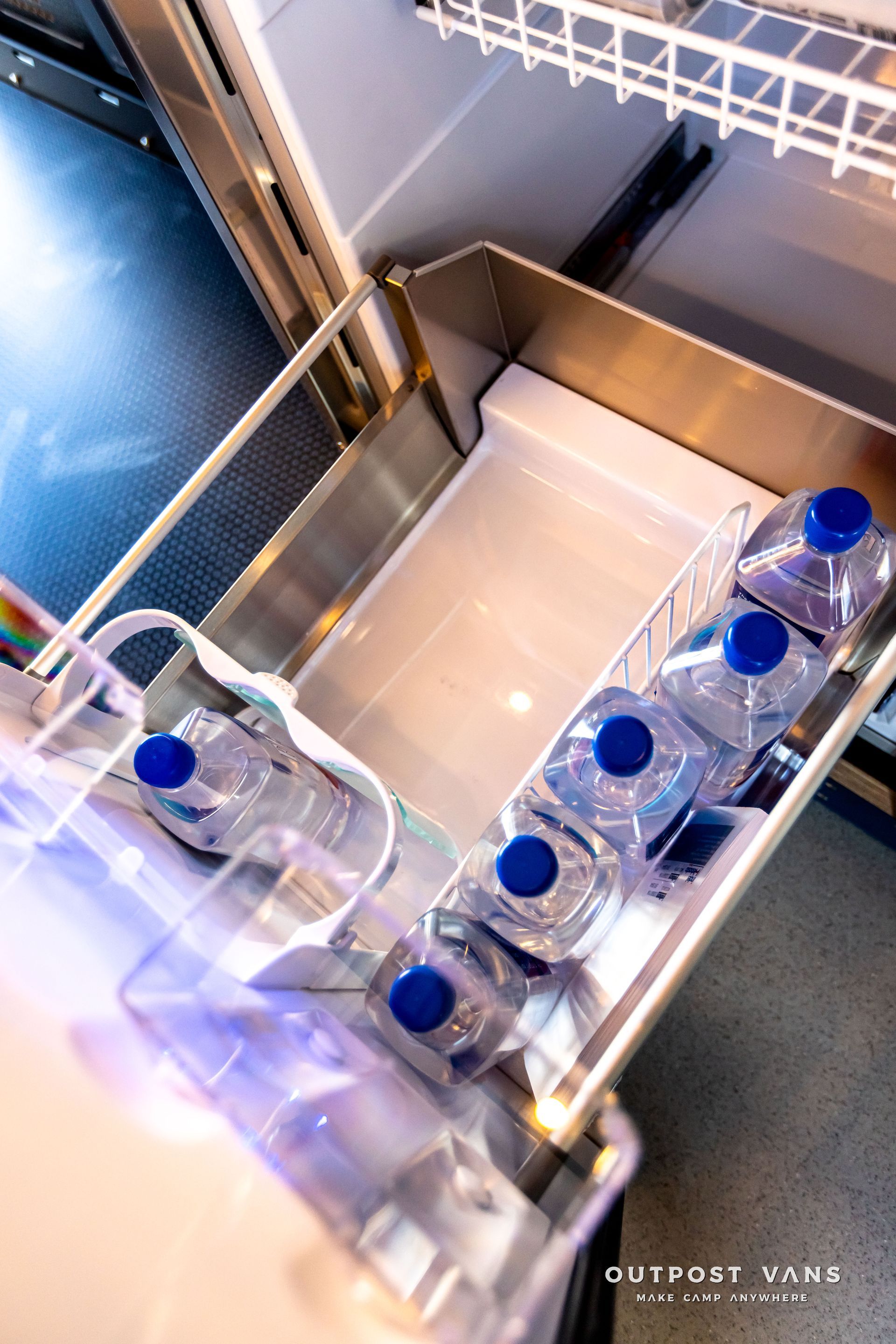 The inside of a refrigerator with bottles of water in it.