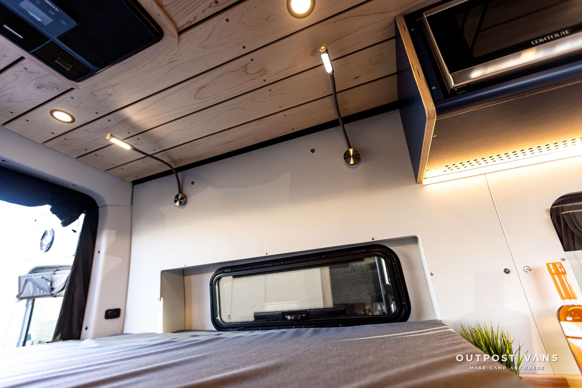 The inside of a van with a bed and a window.