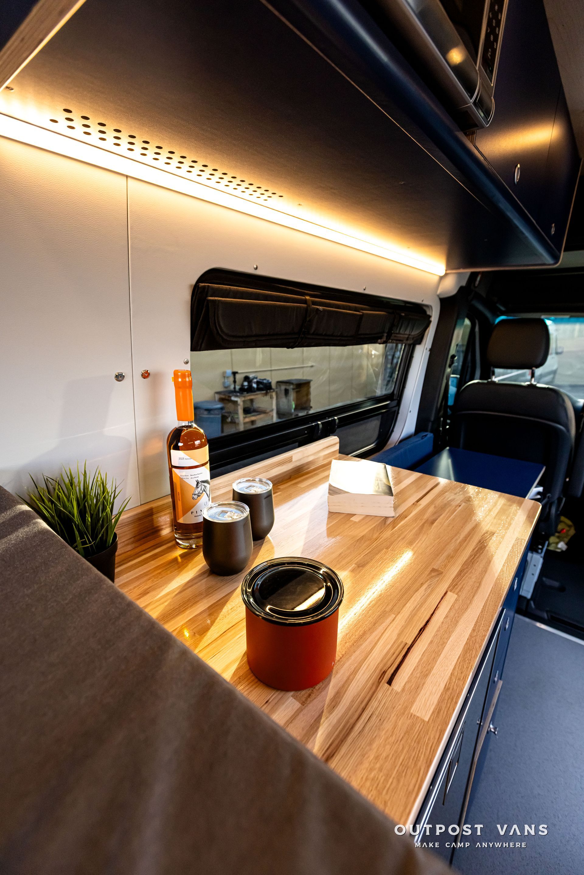 A wooden table with a bottle of wine on it in a van.