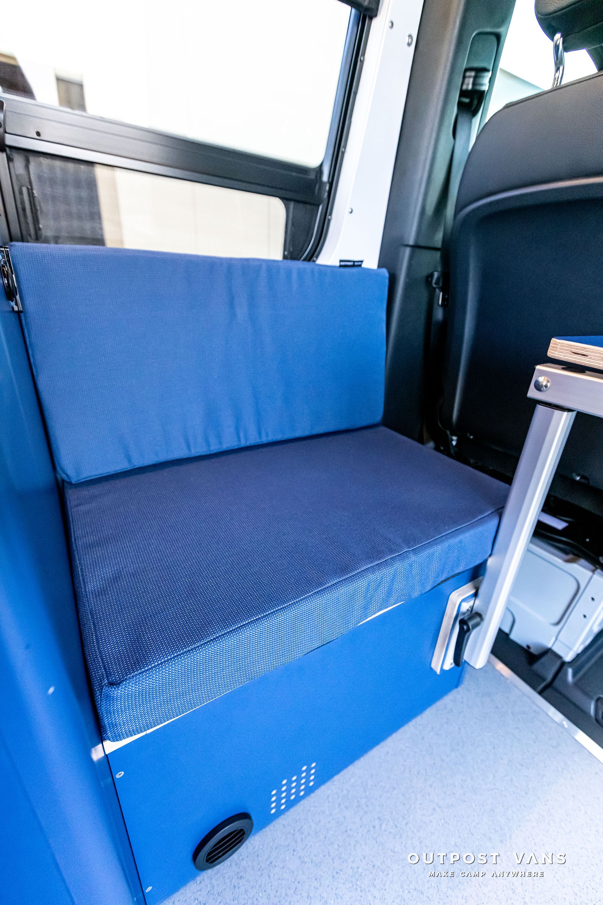 A blue seat in the back of a car with a blue box underneath it.