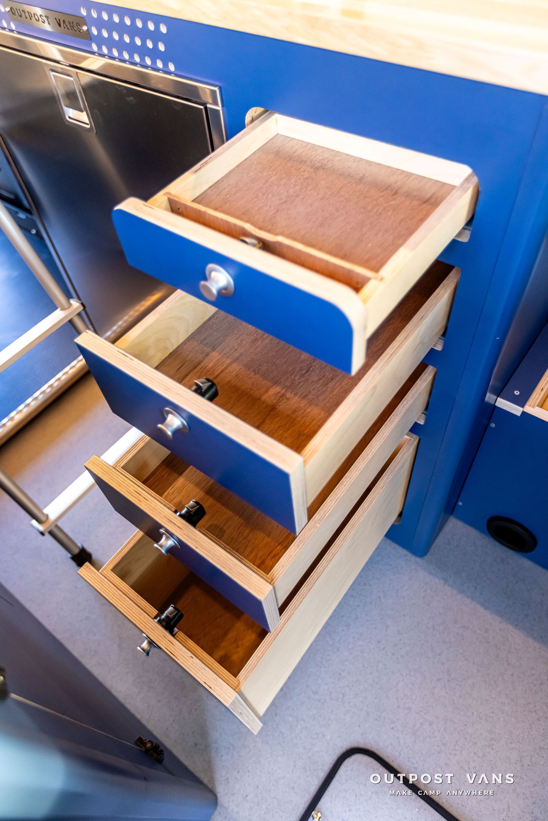 A kitchen with blue cabinets and wooden drawers