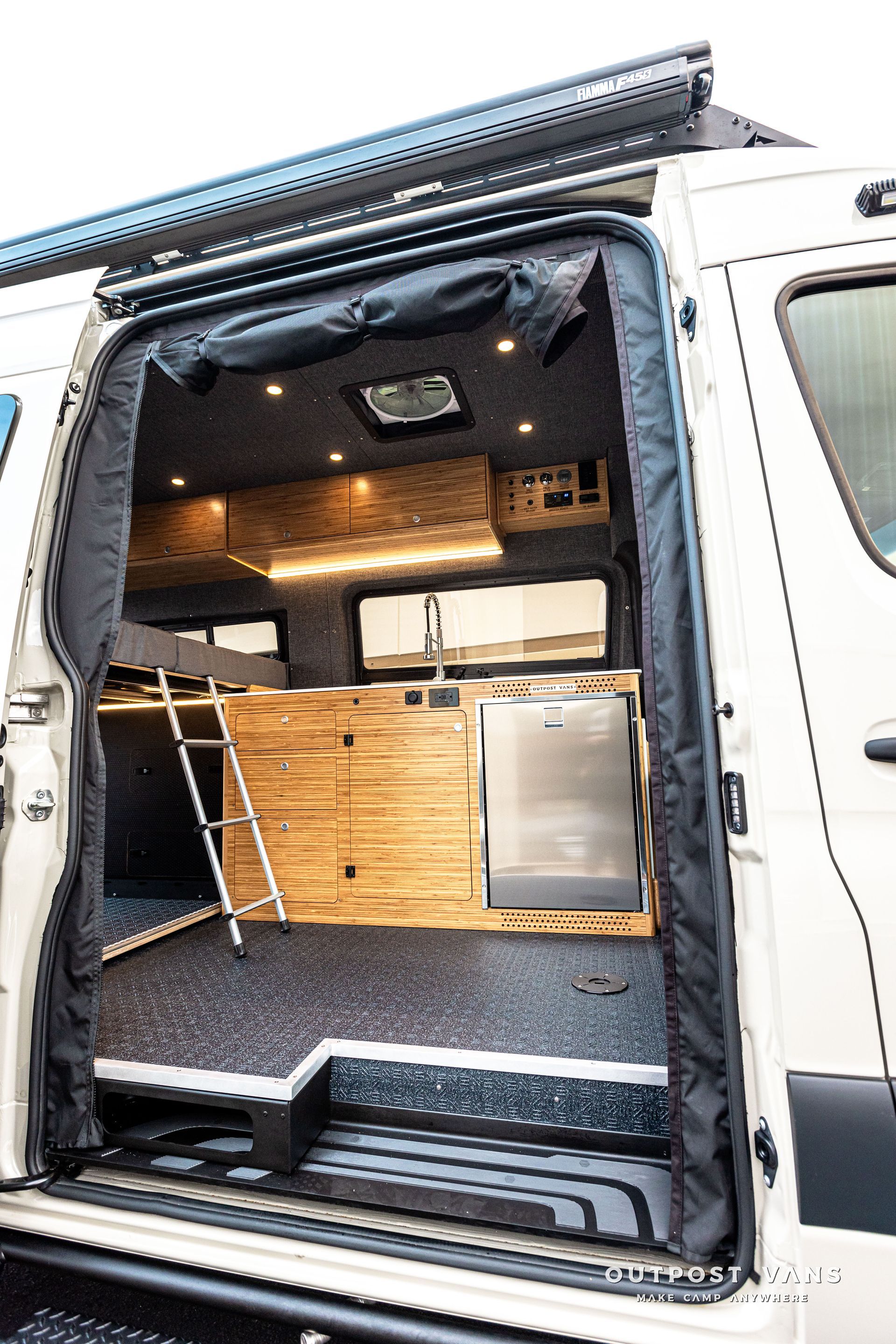 A white van with the door open and a ladder in the back.