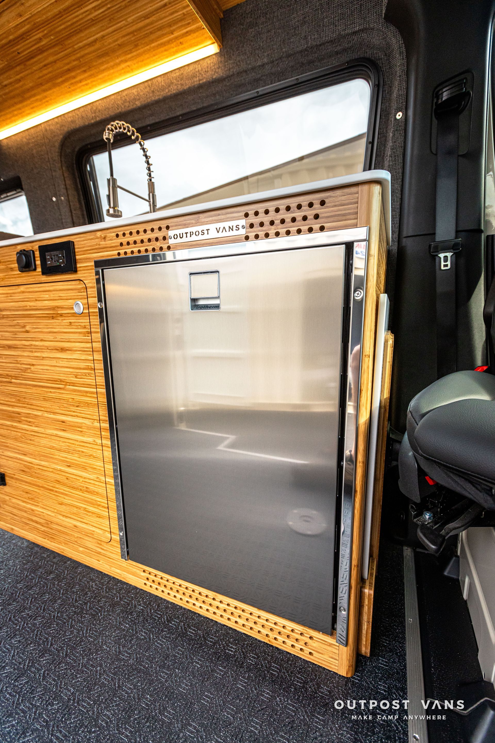 There is a stainless steel refrigerator in the back of a van.