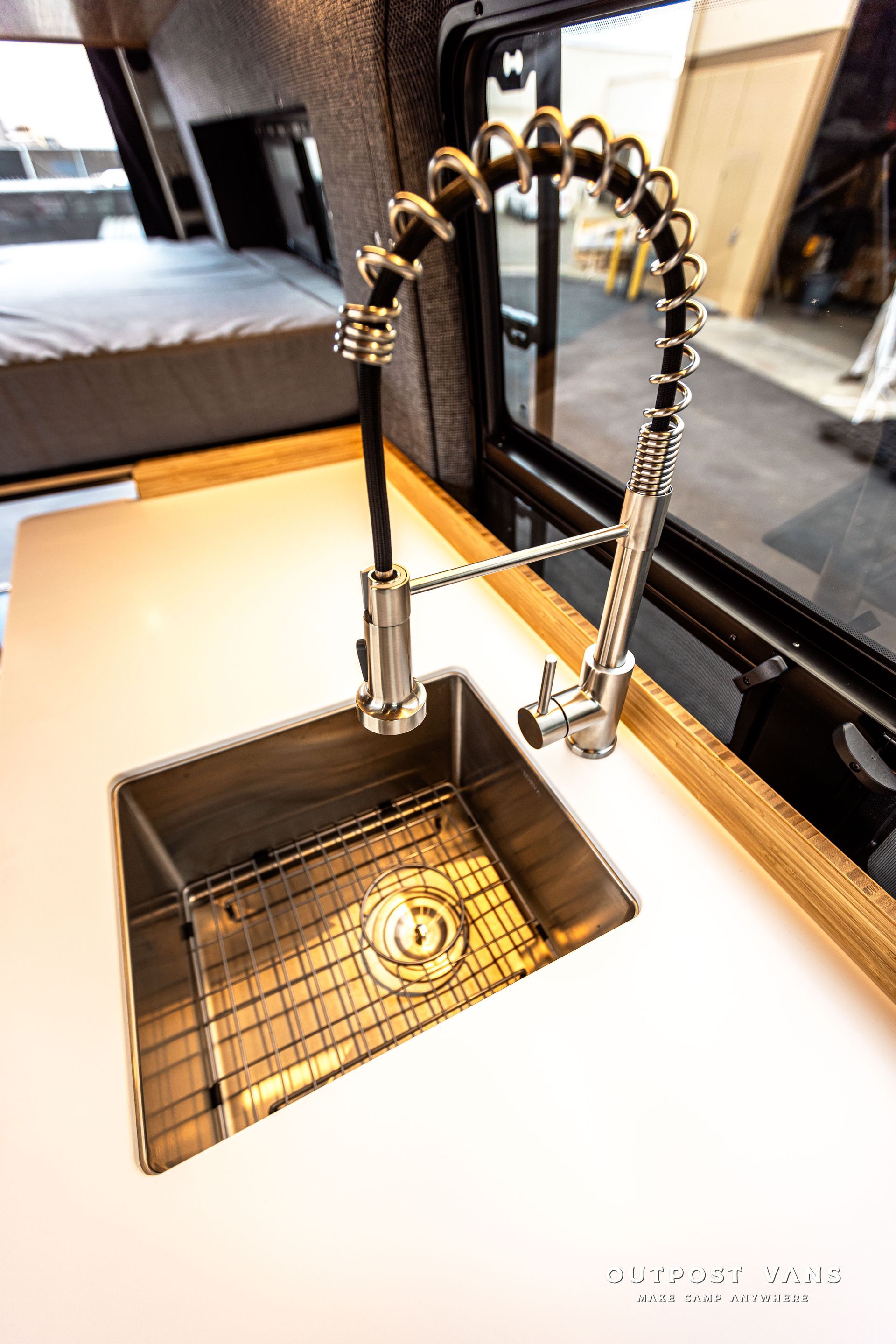 A stainless steel sink with a faucet on a counter in a kitchen.