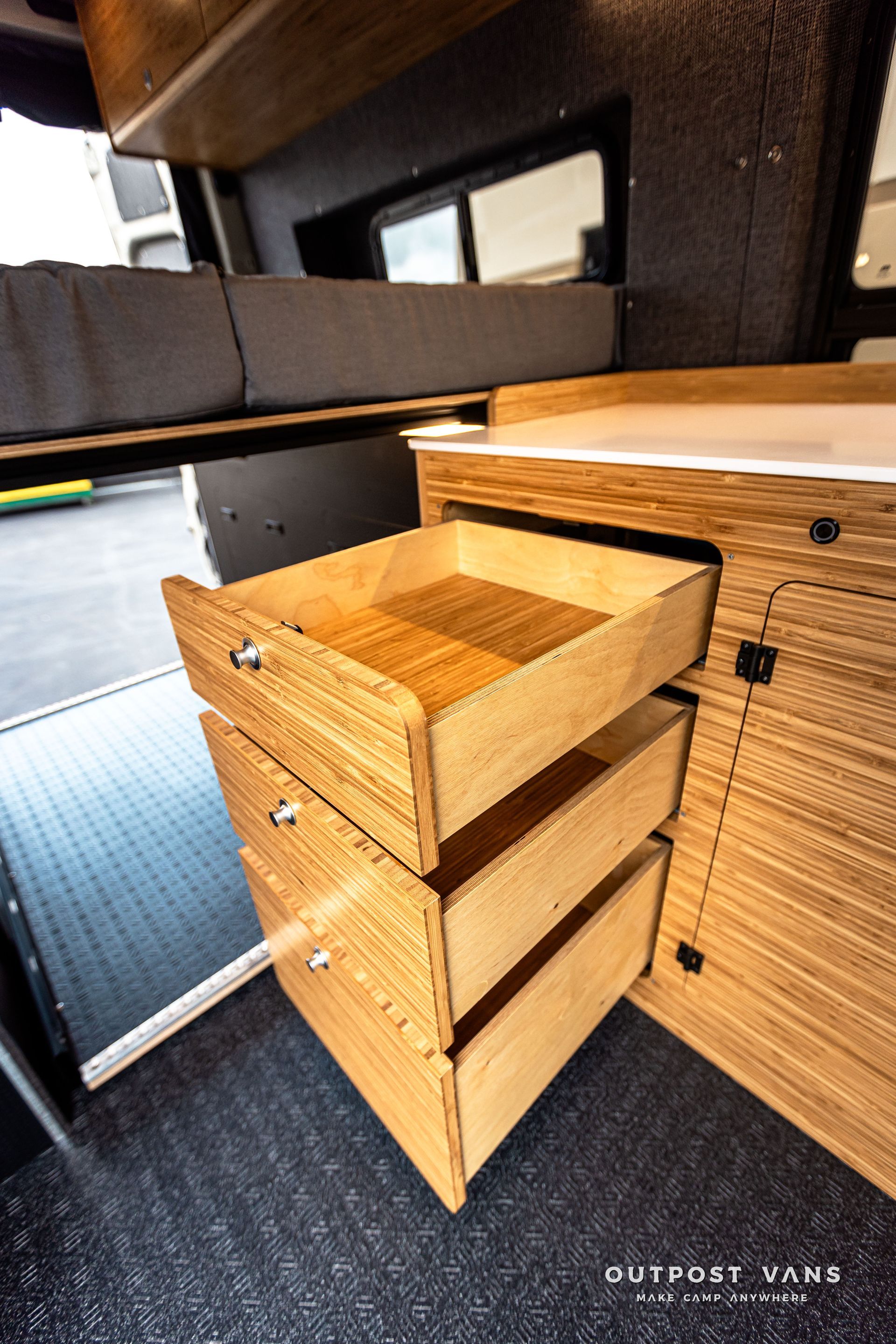 A wooden drawer is open in a camper van.