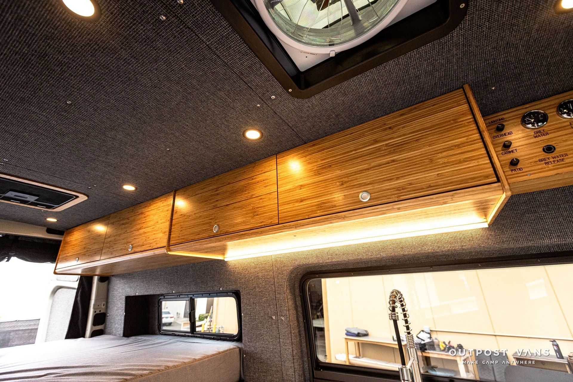 A camper van with a bed and a television on the ceiling.