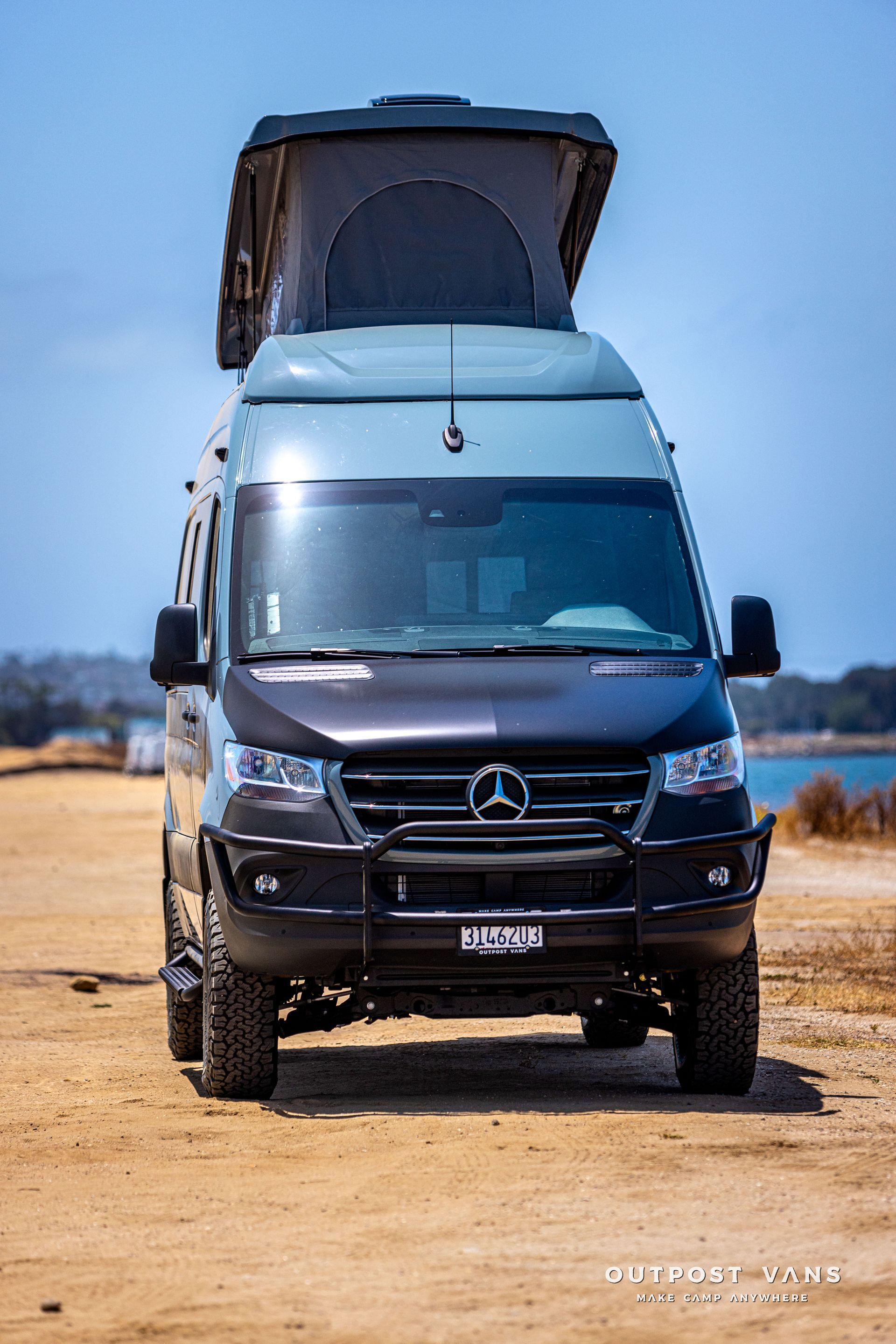 A mercedes sprinter van is parked on a sandy beach.