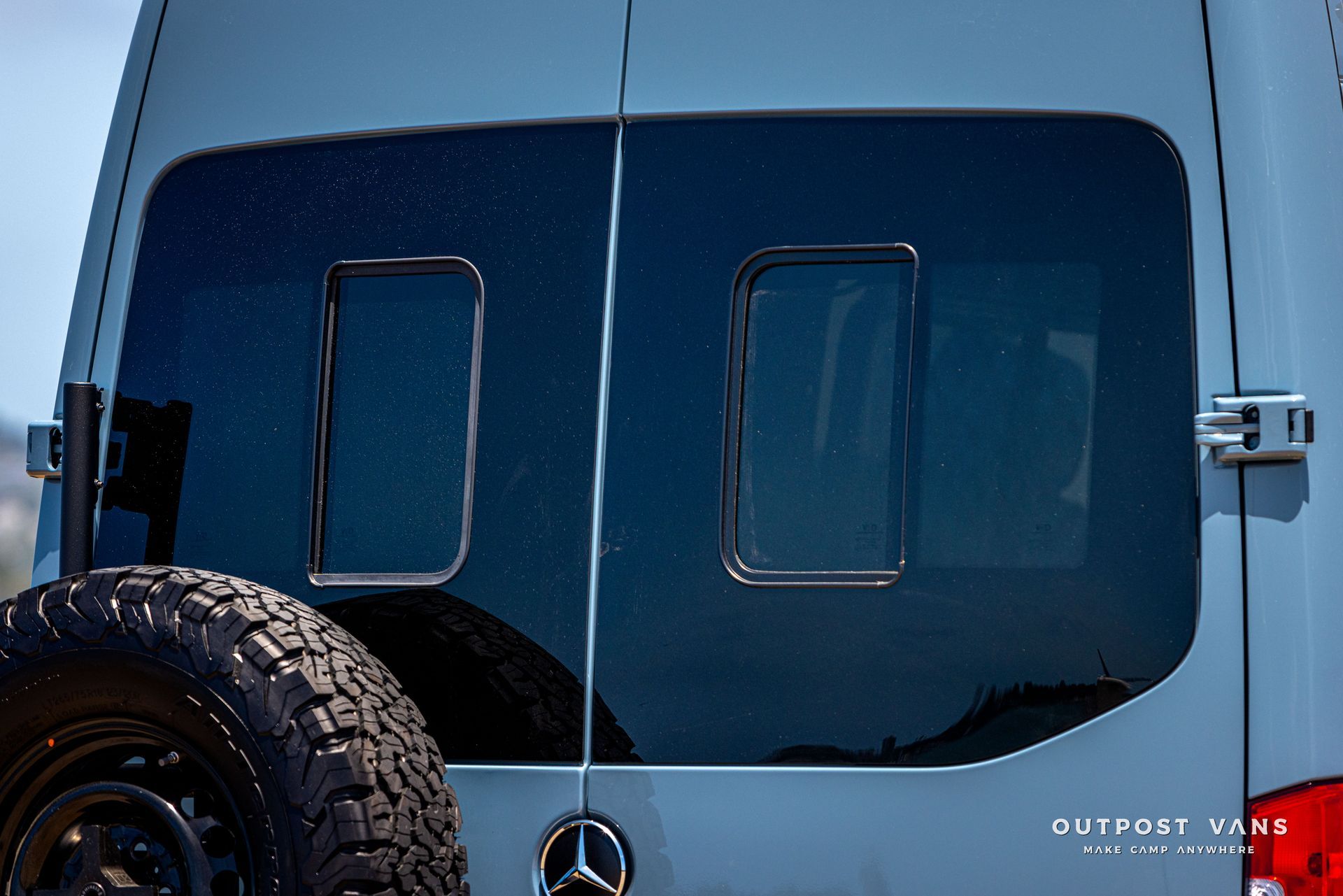 A mercedes van with a large tire on the back