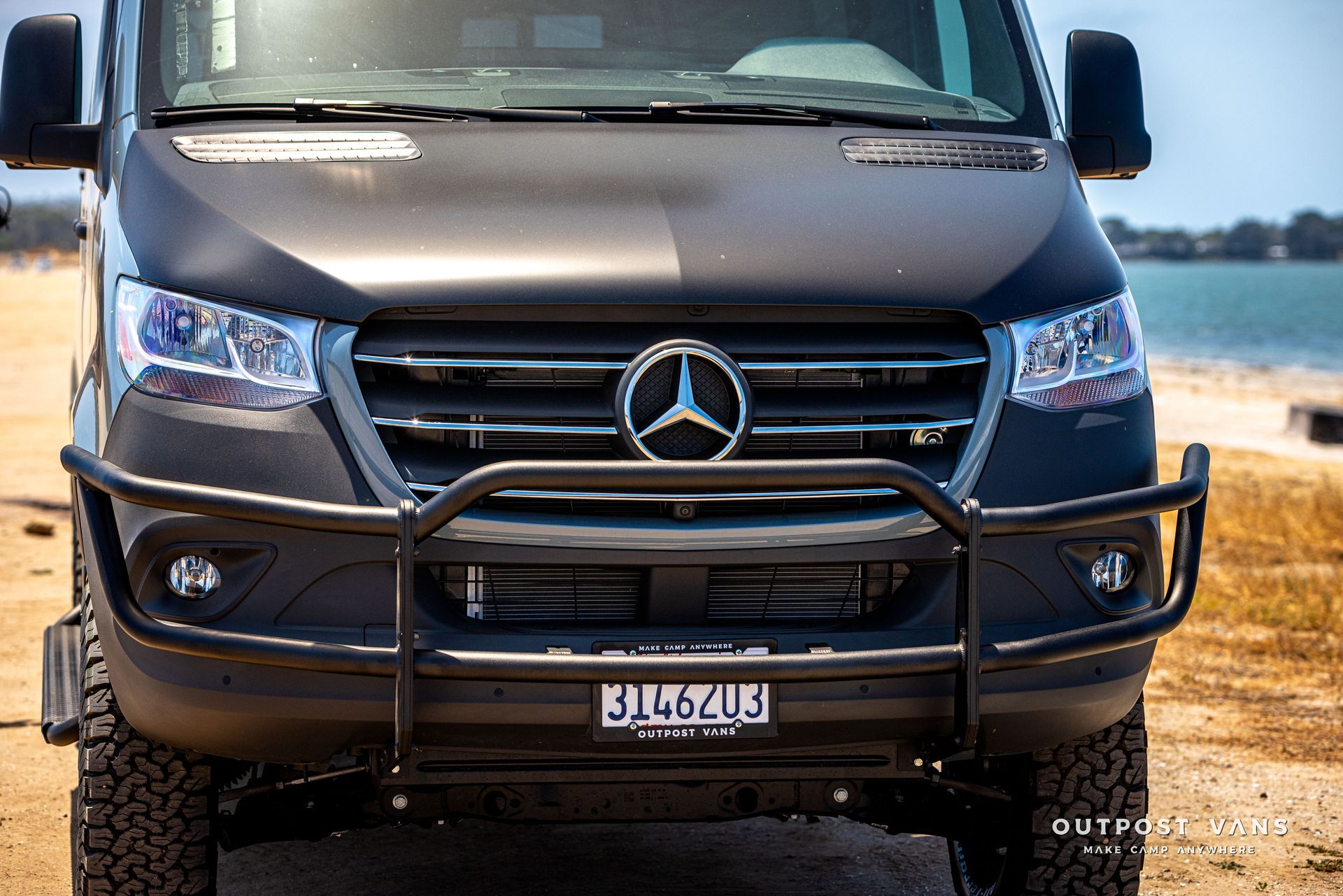 A black mercedes sprinter van is parked on the beach