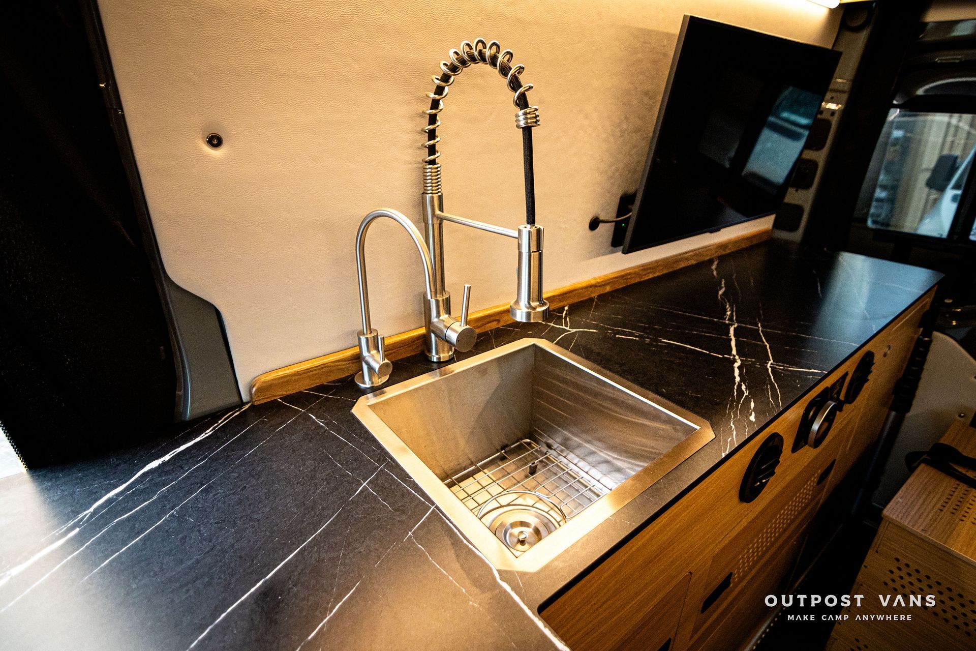 A kitchen sink with a faucet and a black counter top