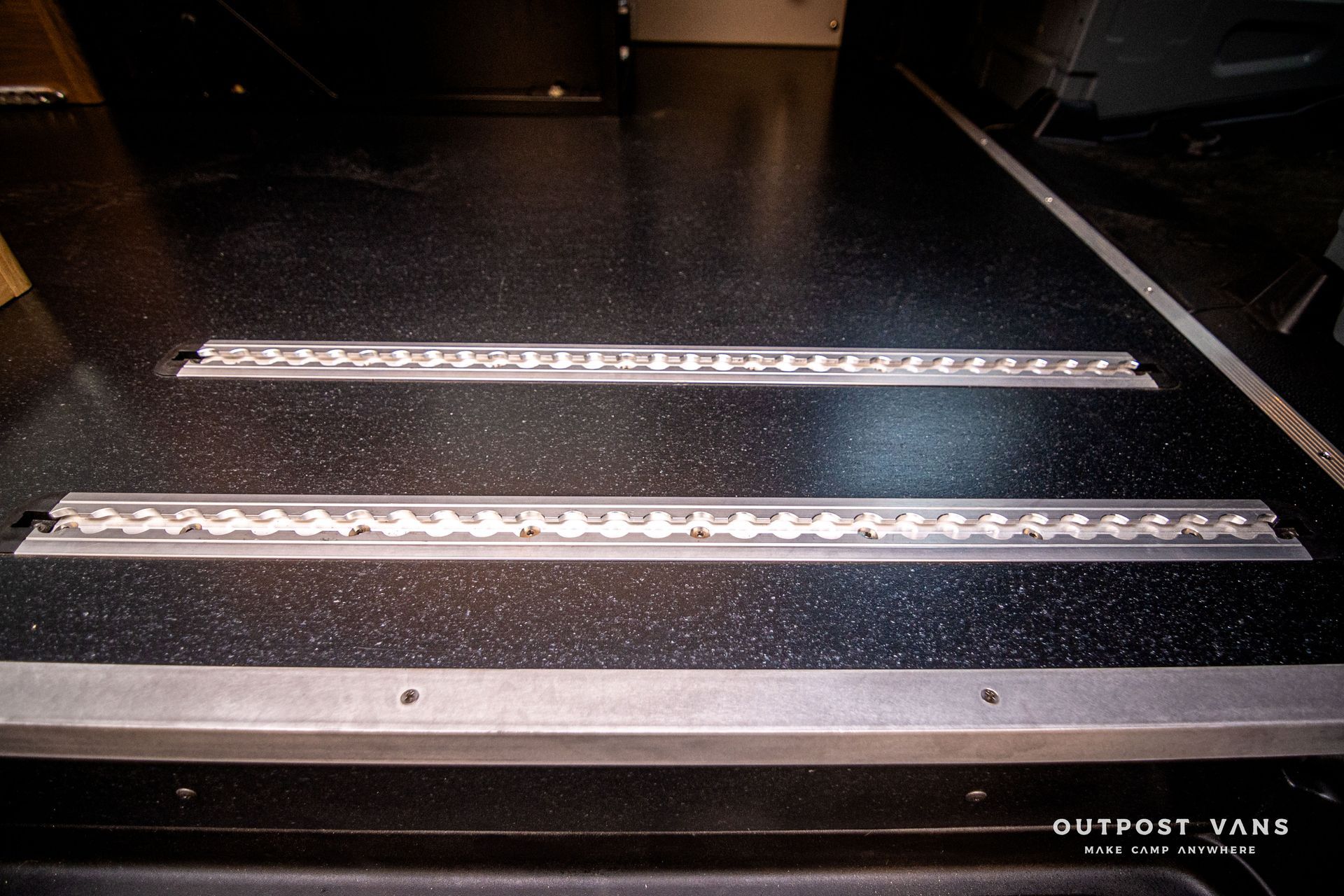 Two metal tracks on a black surface with the word outpost visible