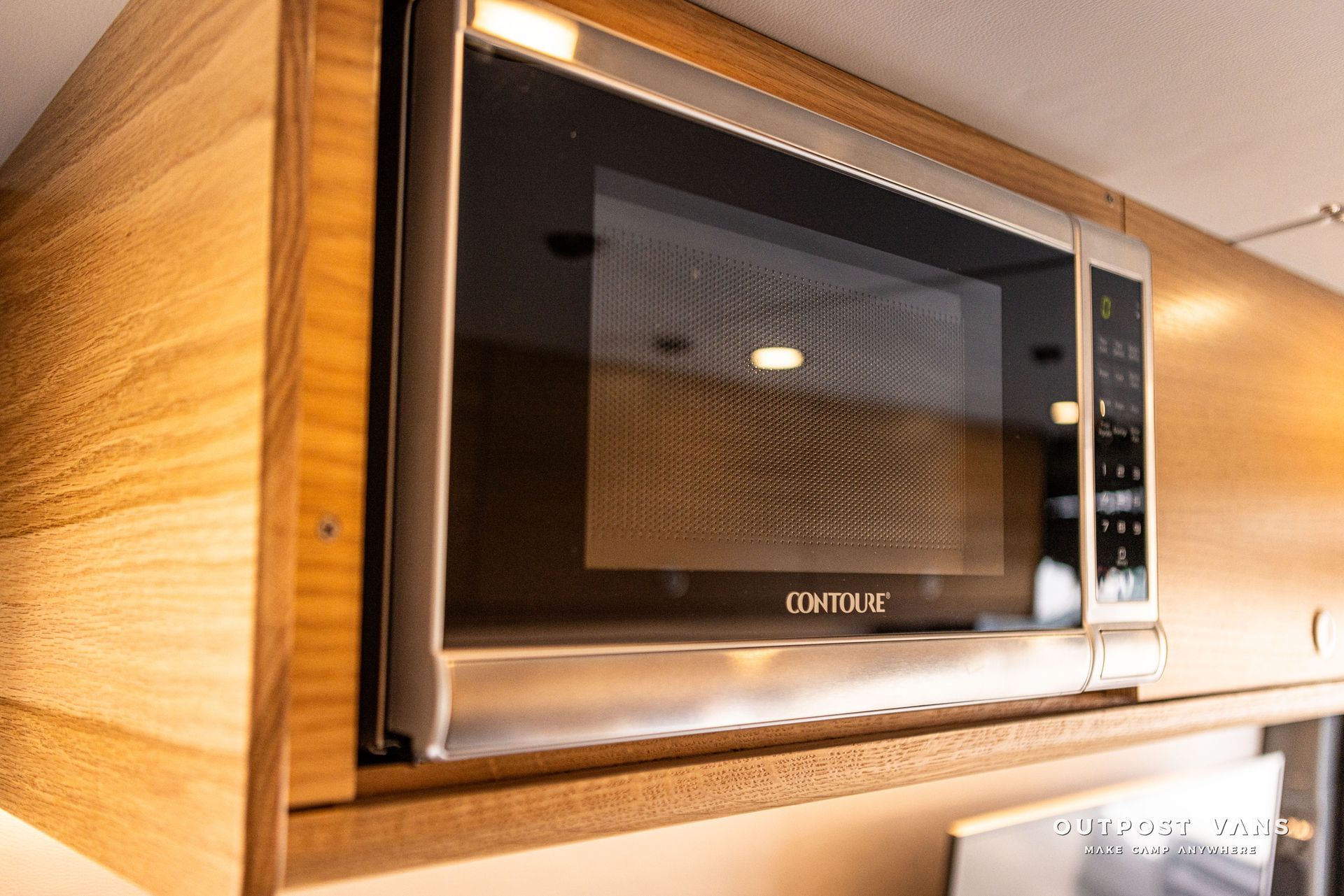 A microwave oven is sitting on top of a wooden cabinet in a kitchen.