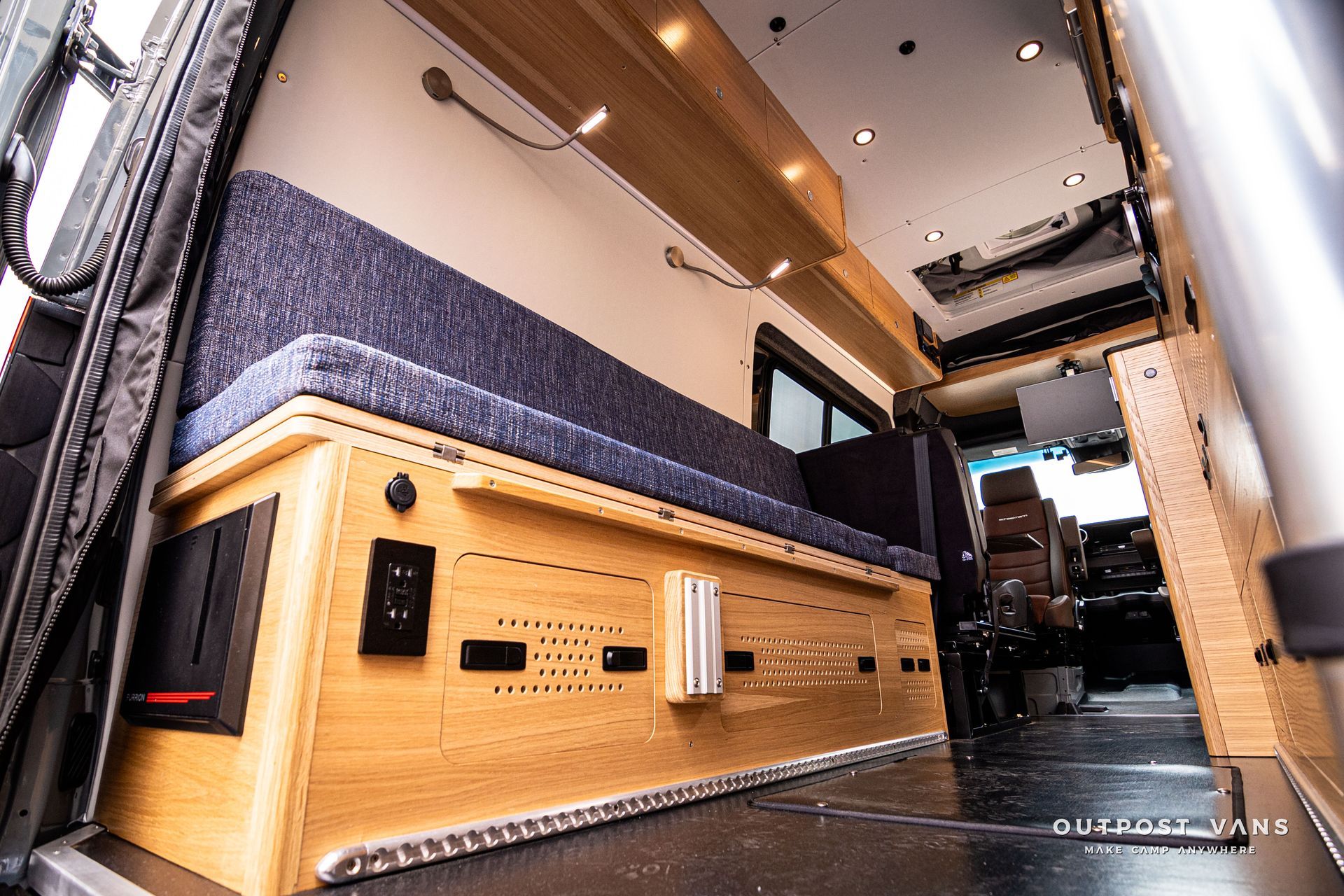 The inside of a van with a wooden bench and a couch.