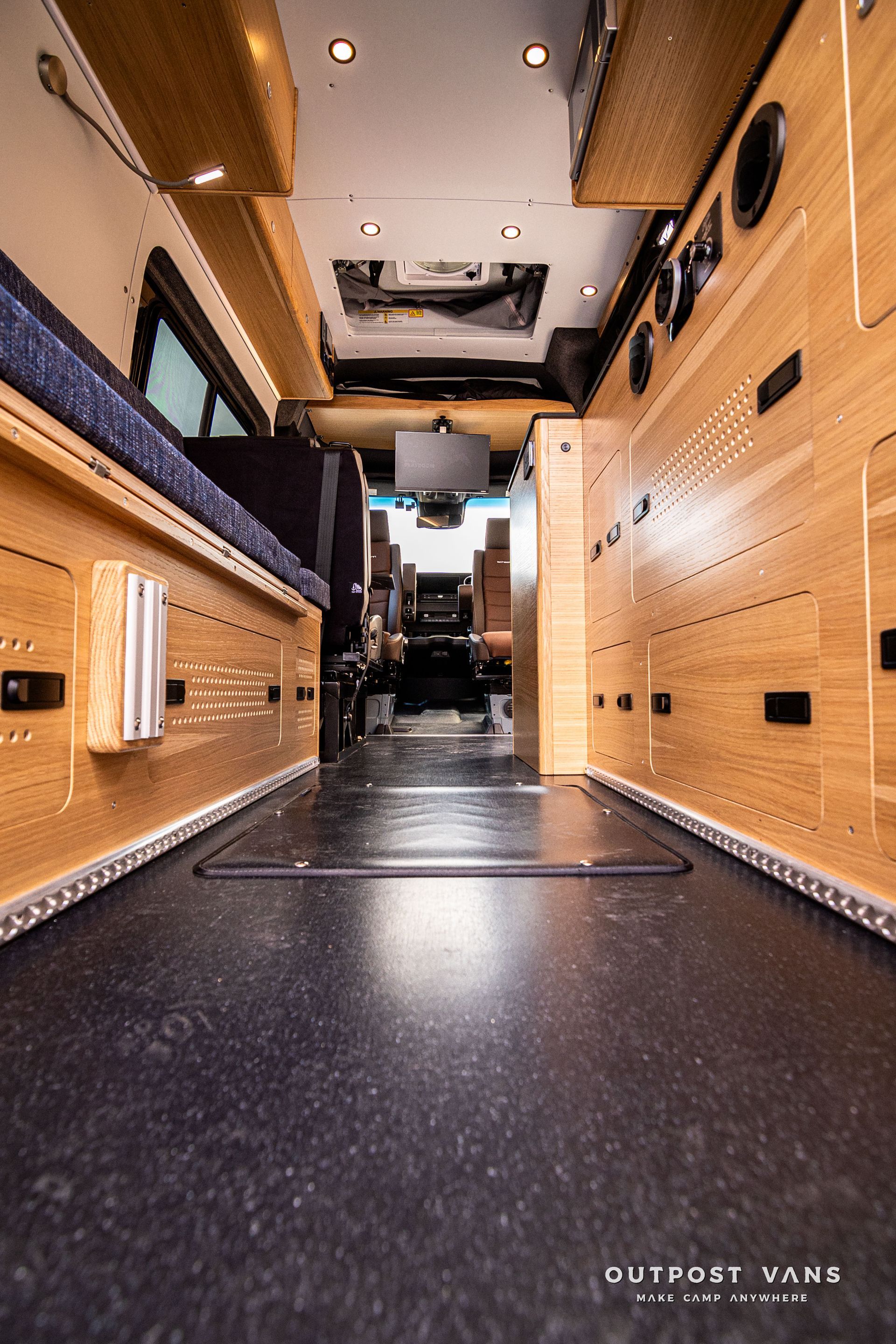 The inside of a van with wooden cabinets and a black floor.